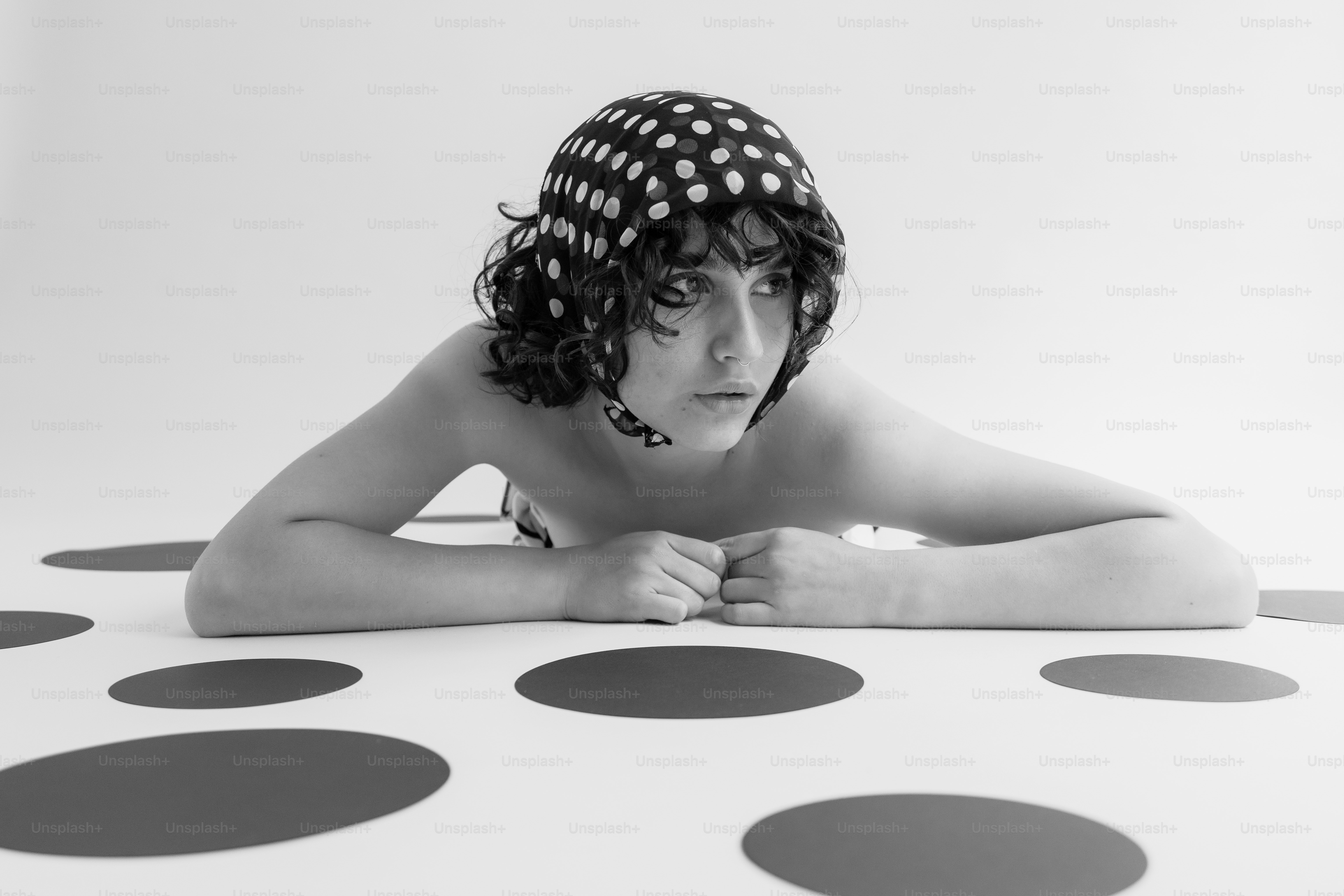 Die Person mit gepunktetem Kopfschmuck liegt auf einer gepunkteten Oberfläche