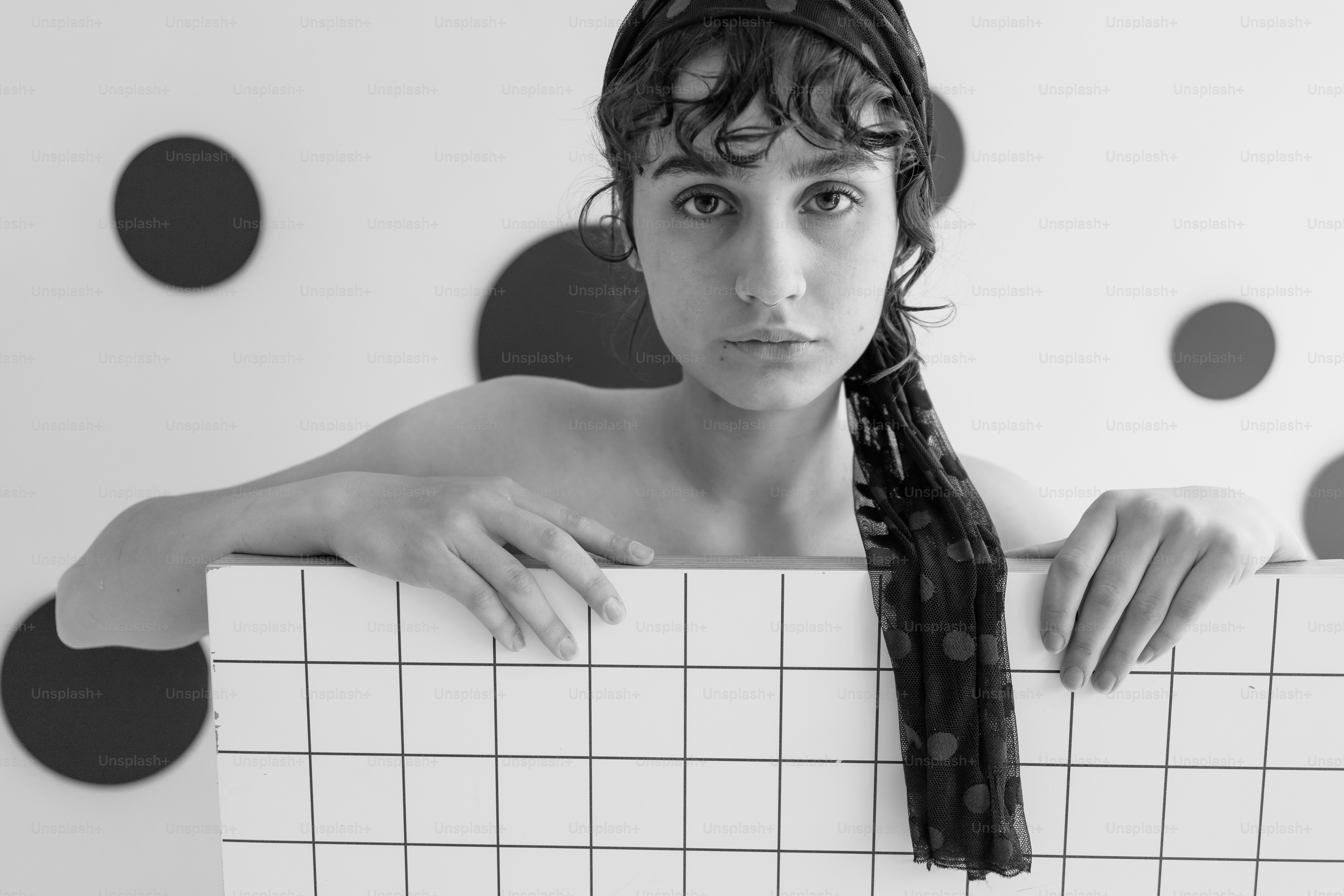 Frau mit Schal hinter gefliester Wand in Schwarz-Weiß