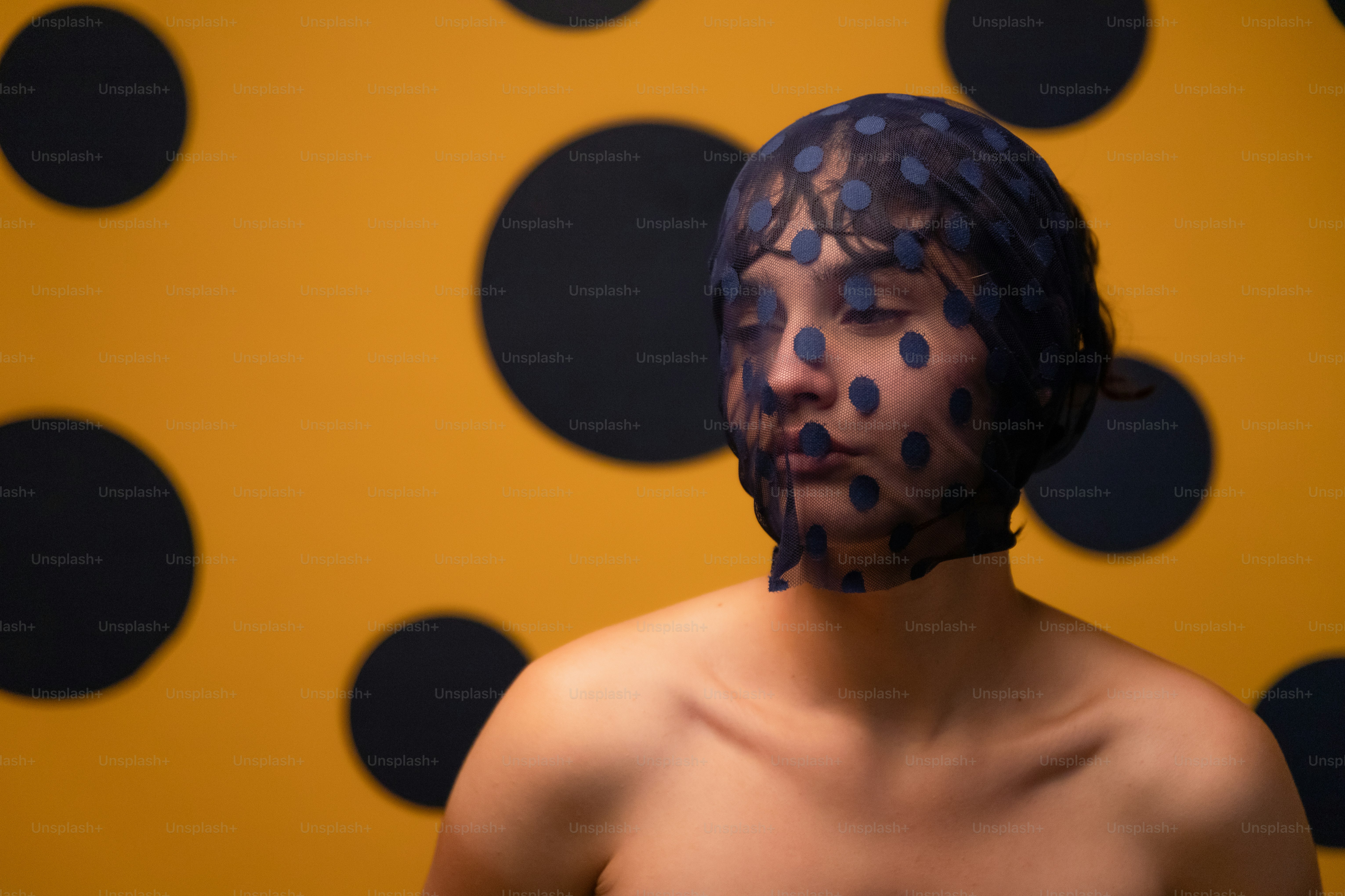 Frau mit gepunktetem Schleier vor gelbem Hintergrund