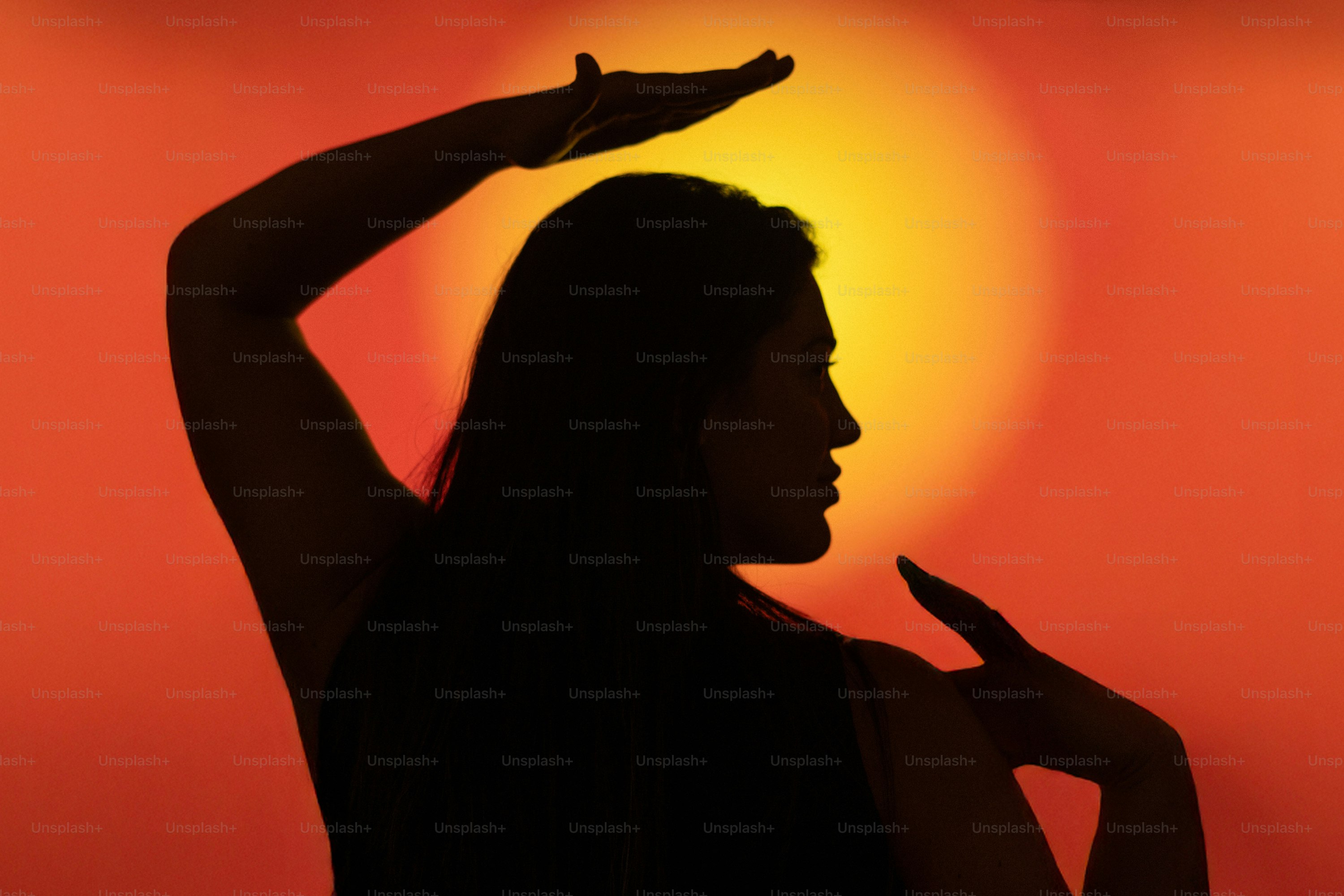 Silhouette of a woman with arms raised against sunset.