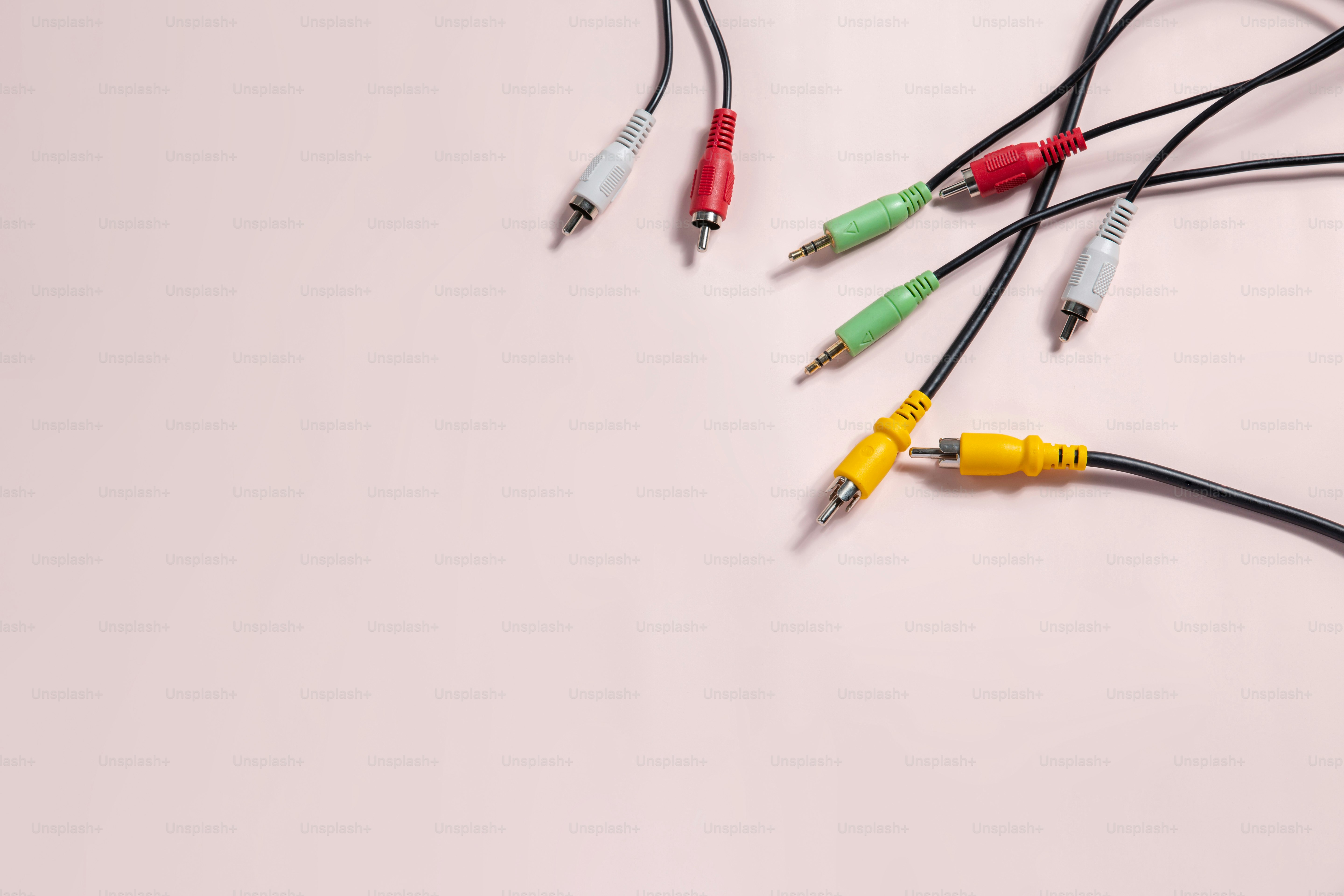 Various colored audio-visual cables on a pink background