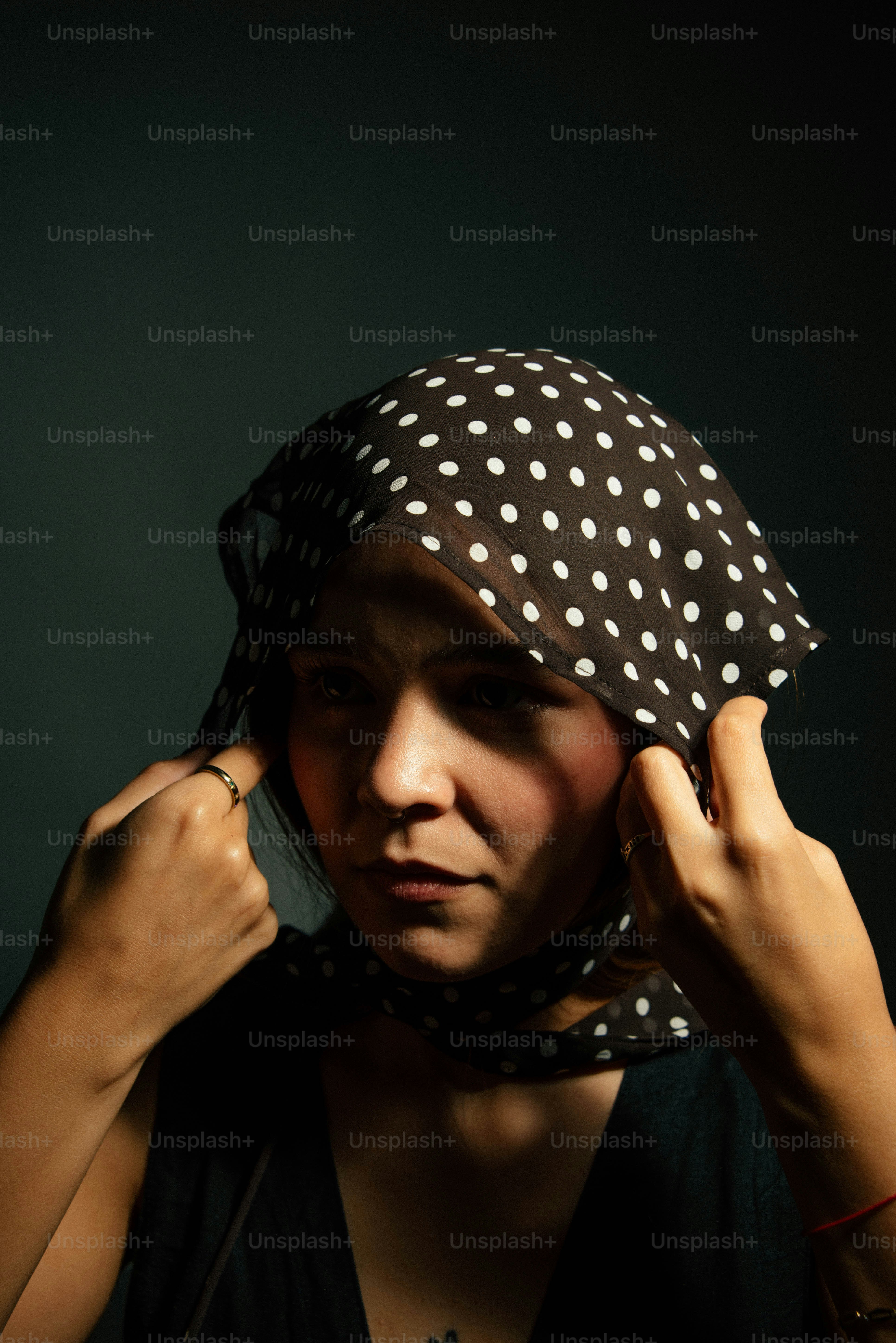 Woman adjusting polka dot headscarf with hands