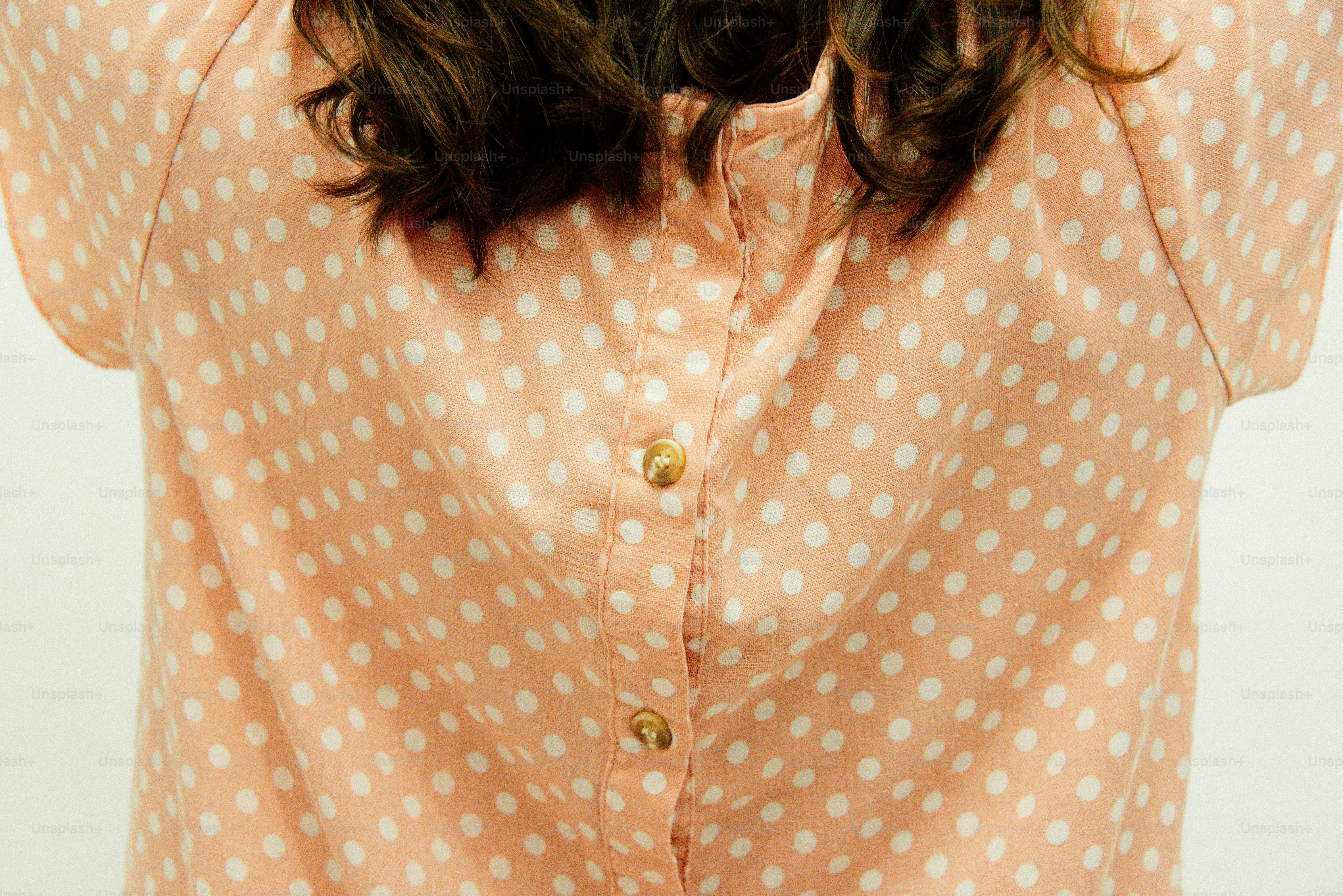 Primer plano de una blusa de lunares melocotón con botones