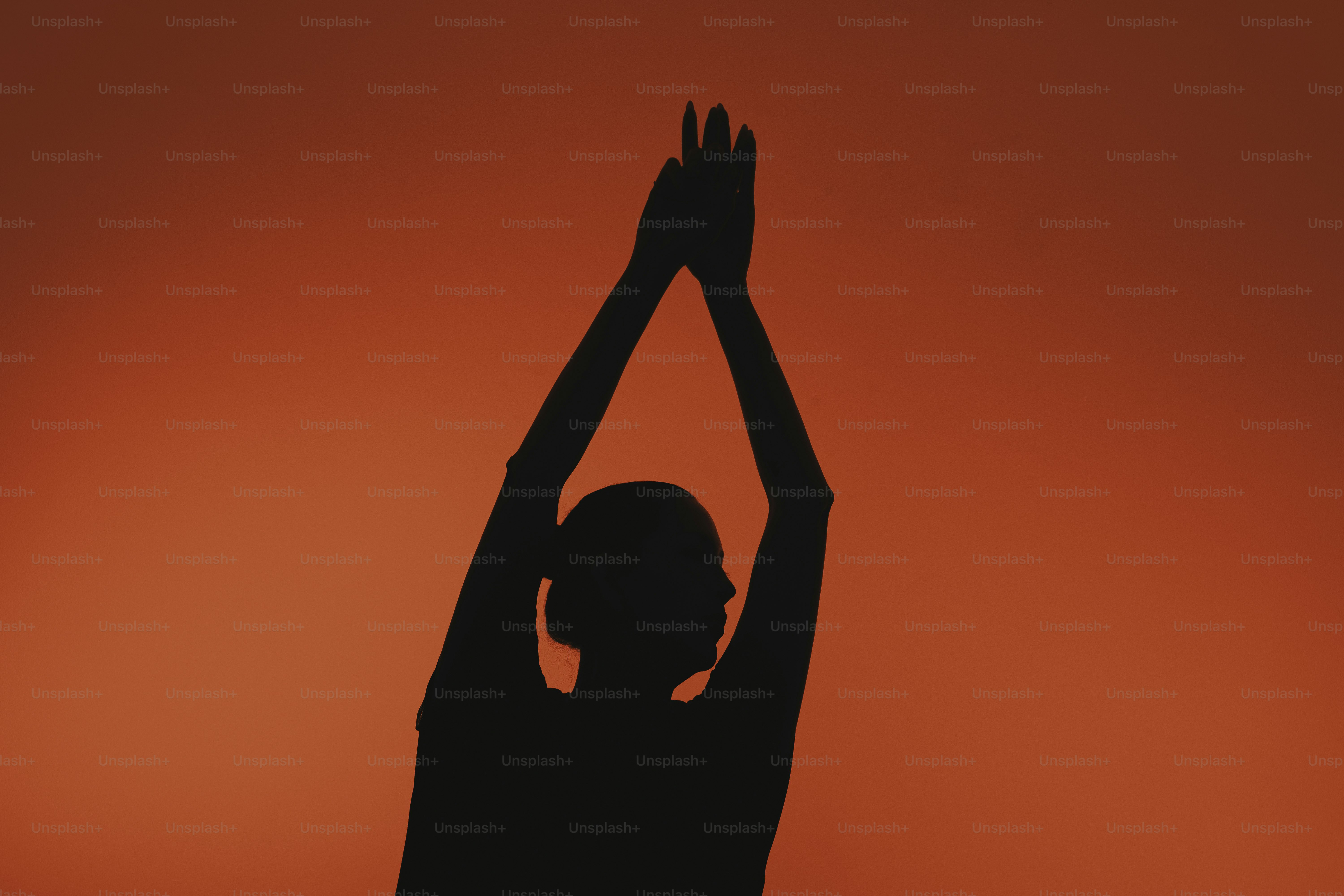 Shadow of person with arms raised against red background