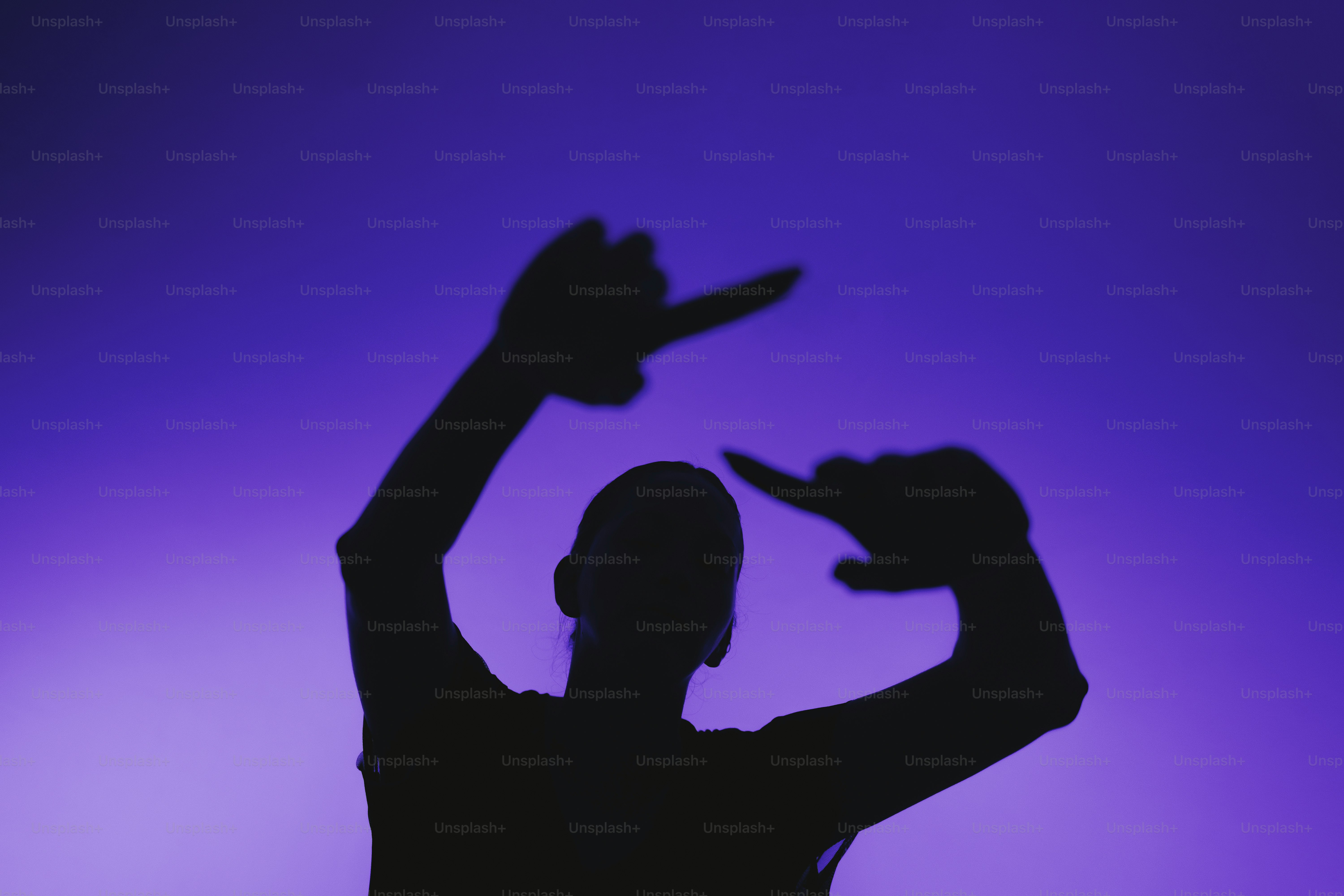Silhouette of a person framing with hands against blue background