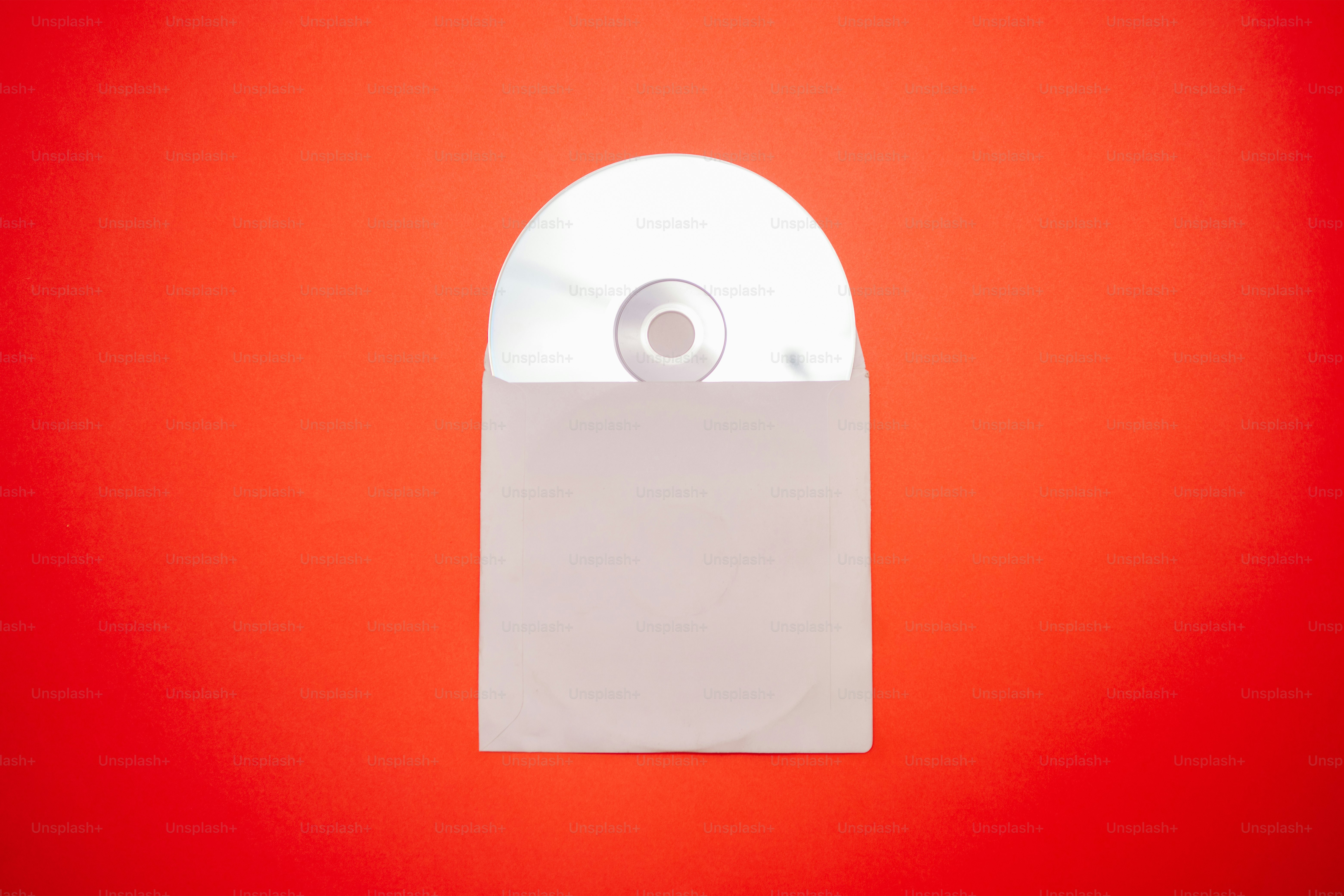 A white cd in a paper sleeve on red background