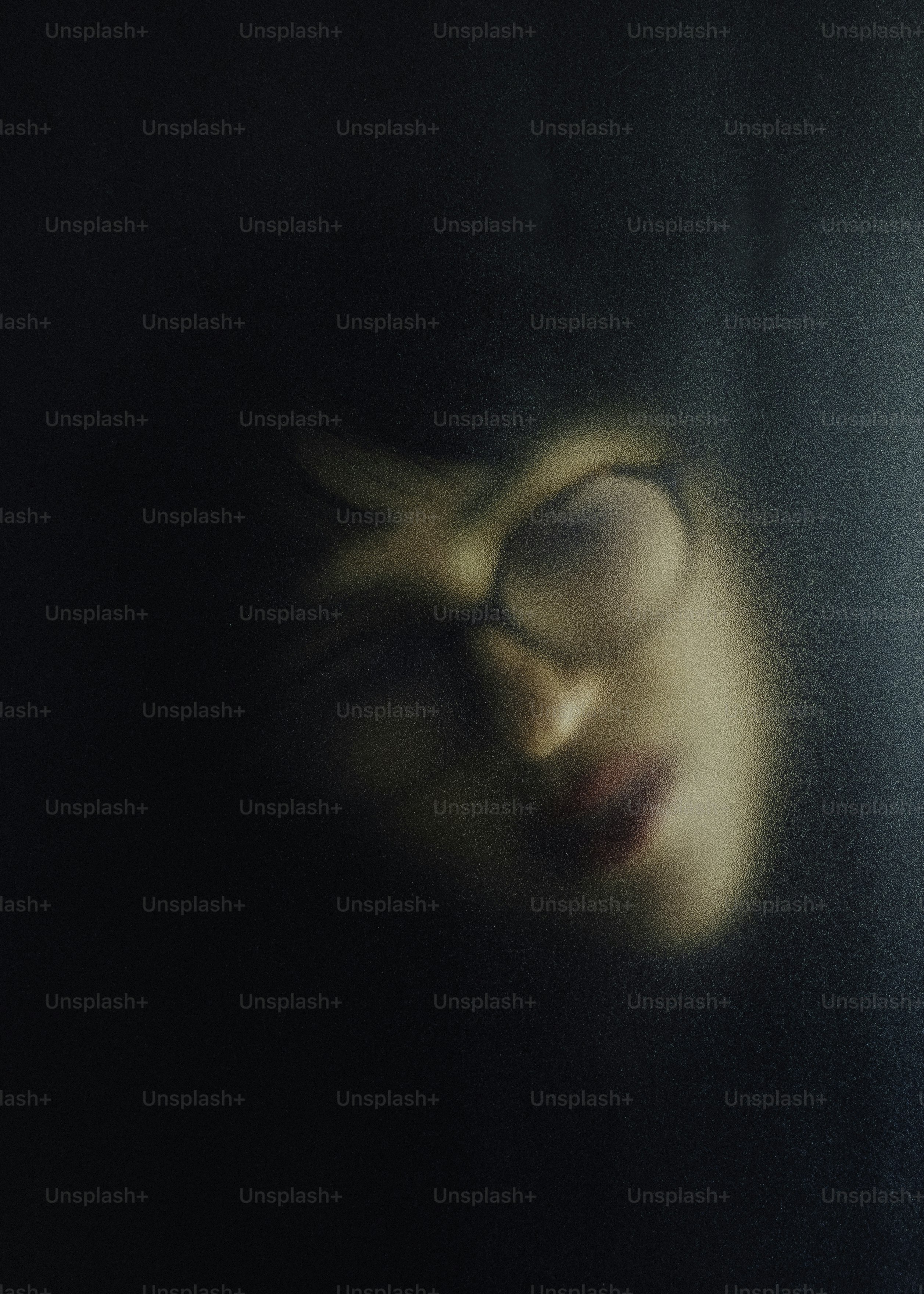 A person wearing glasses seen through frosted glass.