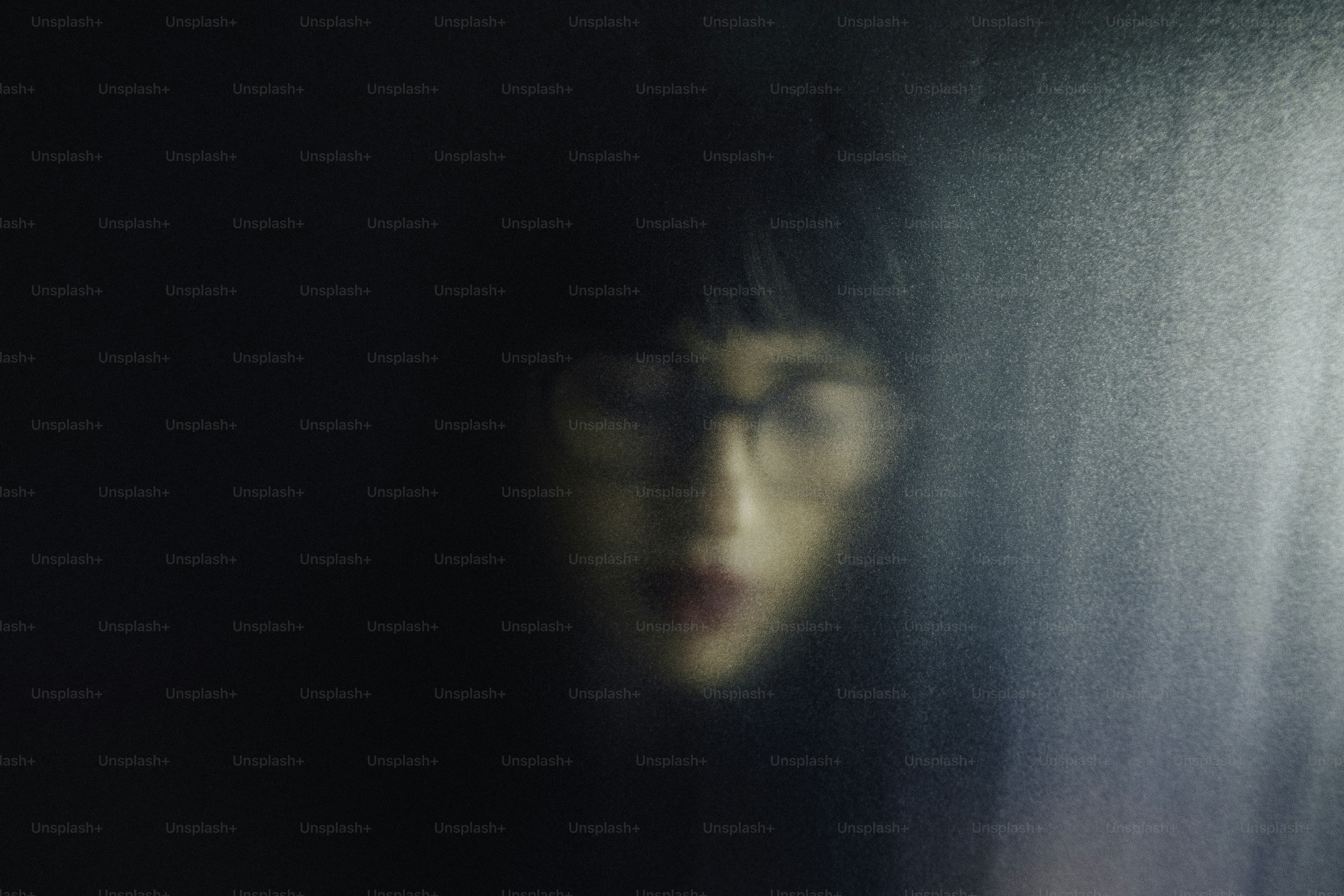 A blurred portrait of a woman with glasses.