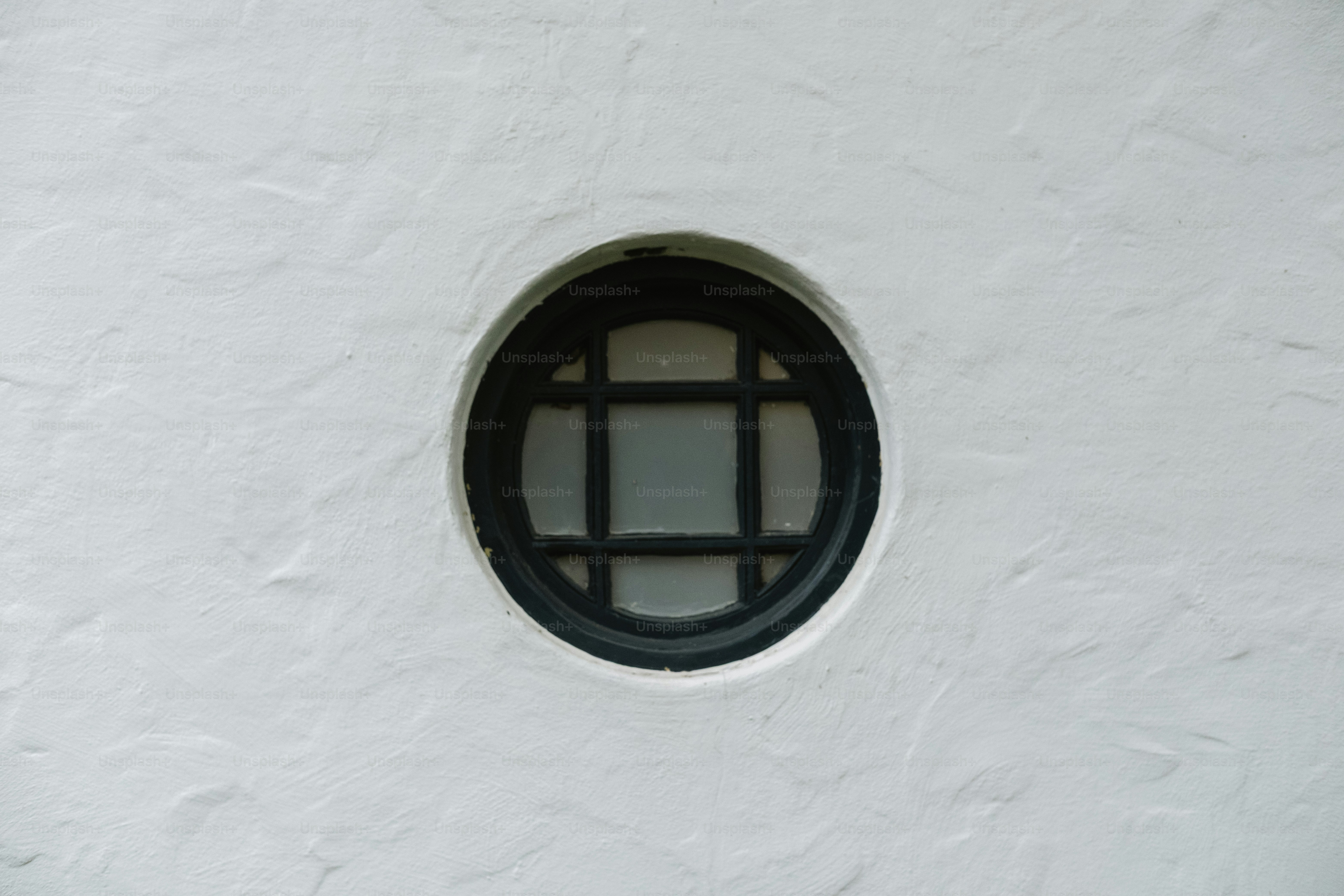 Une petite fenêtre ronde avec un motif en grille.