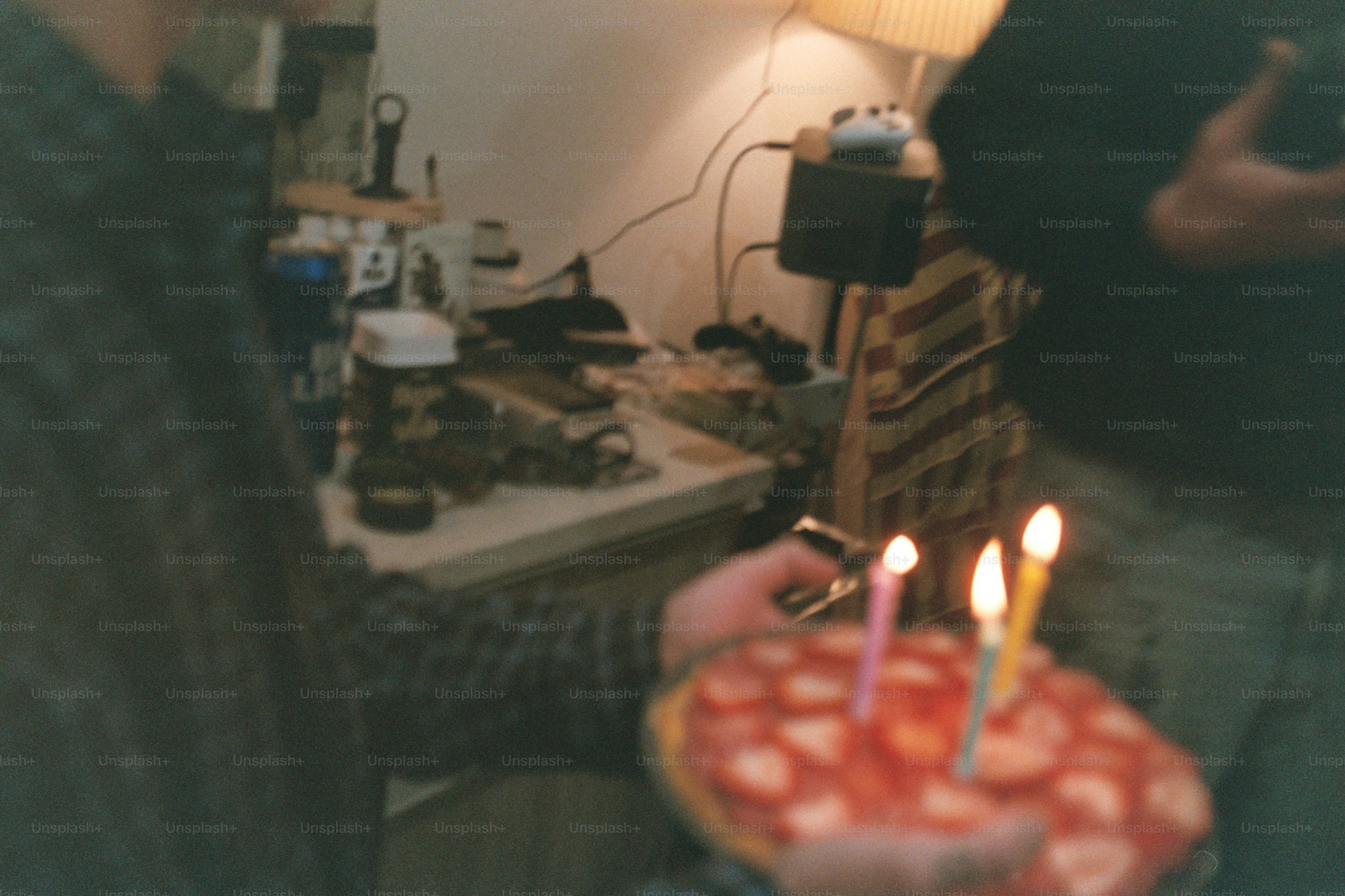 Person lighting candles on a strawberry cake