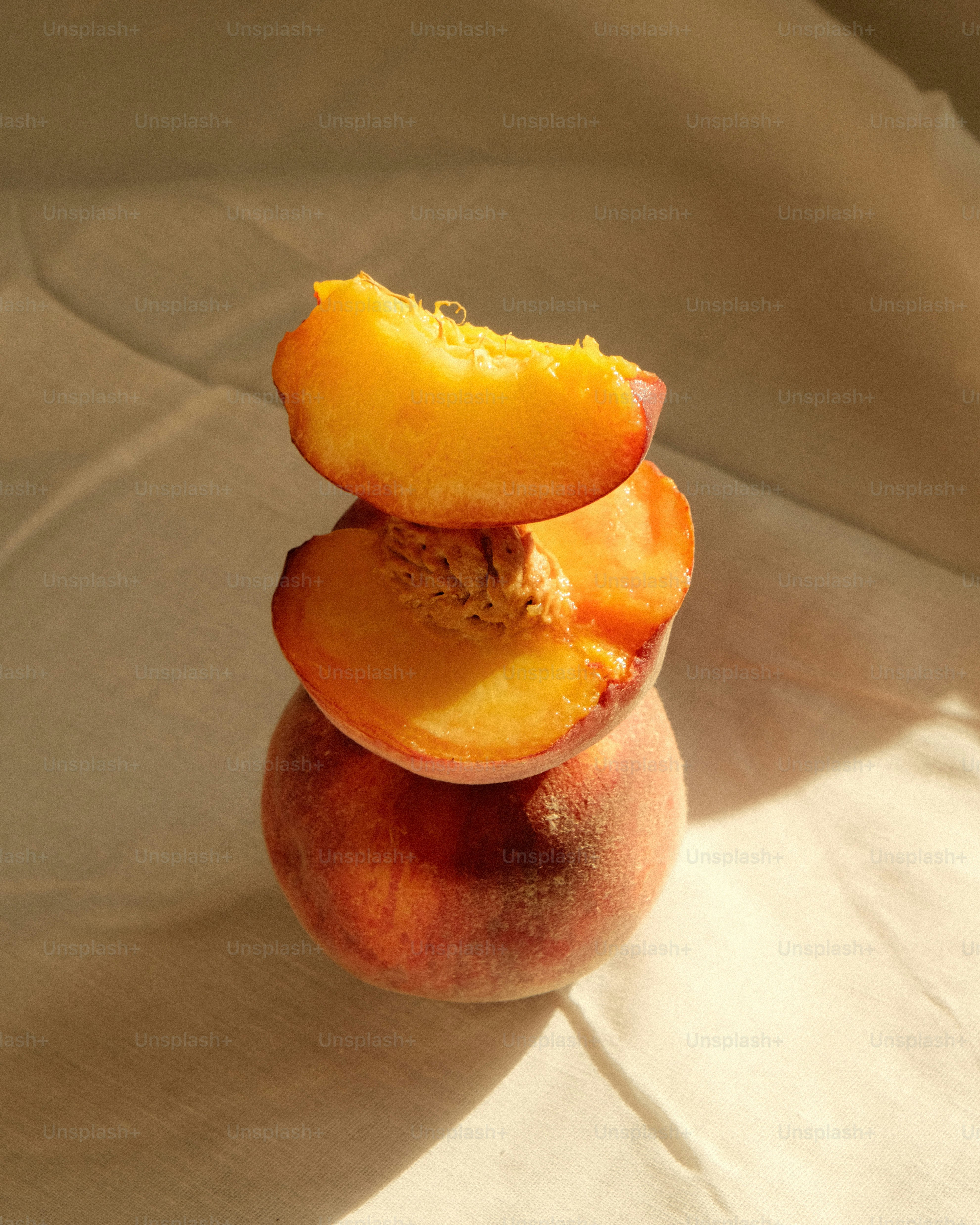 Stack of sliced peaches on a white cloth.