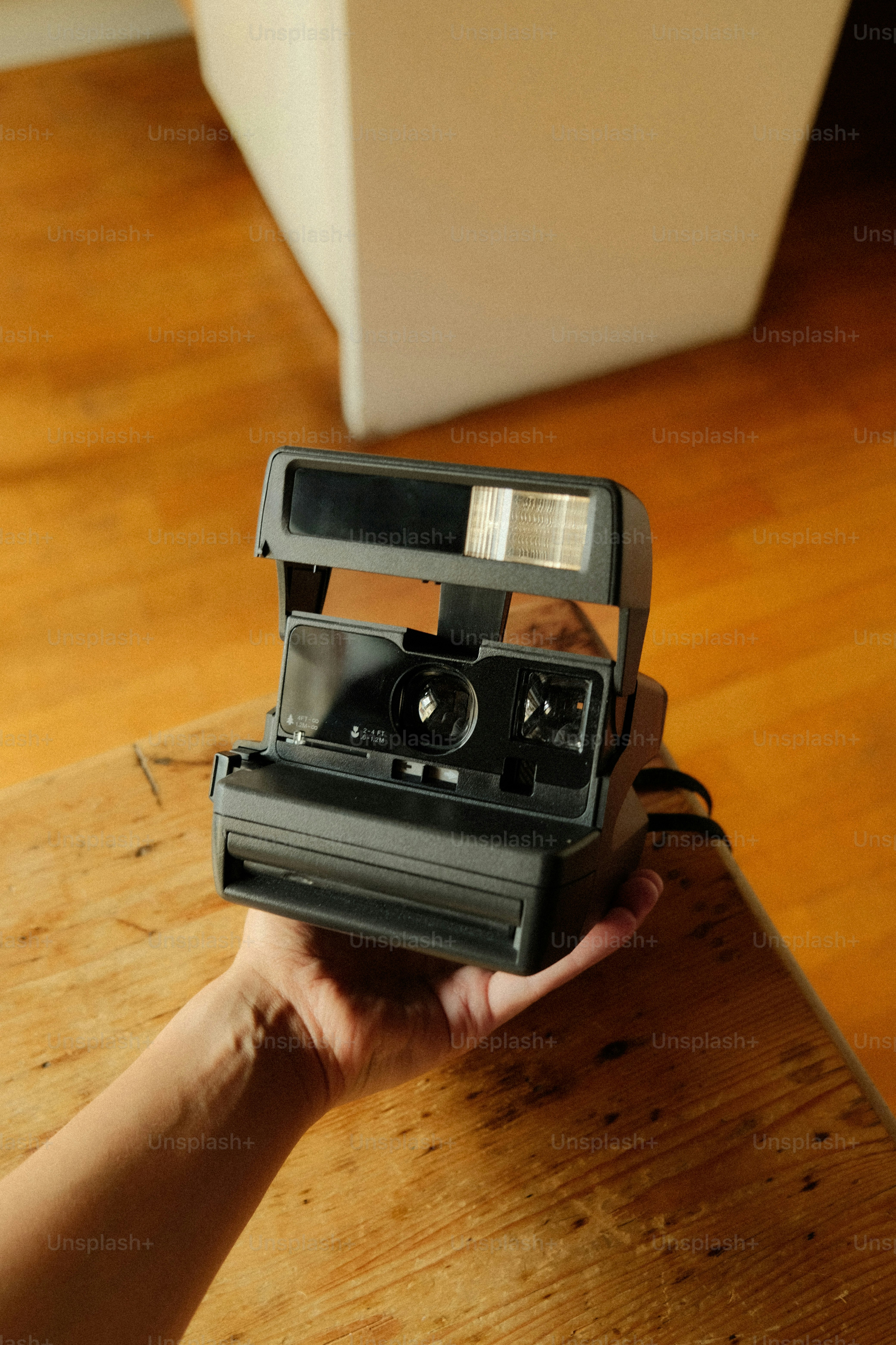 Hand holding a vintage instant camera on wooden table