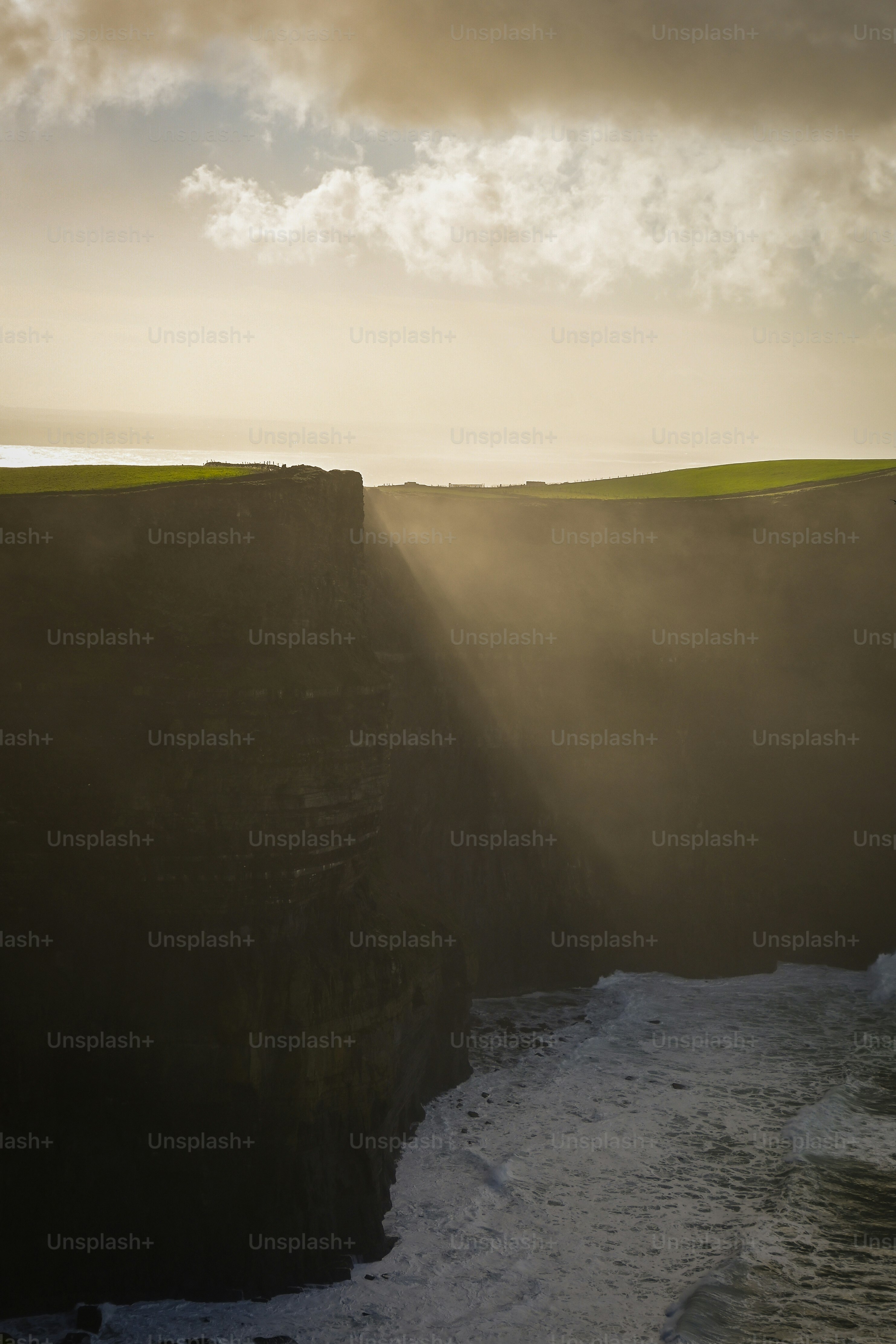 Sunbeams pierce fog over ocean cliffs