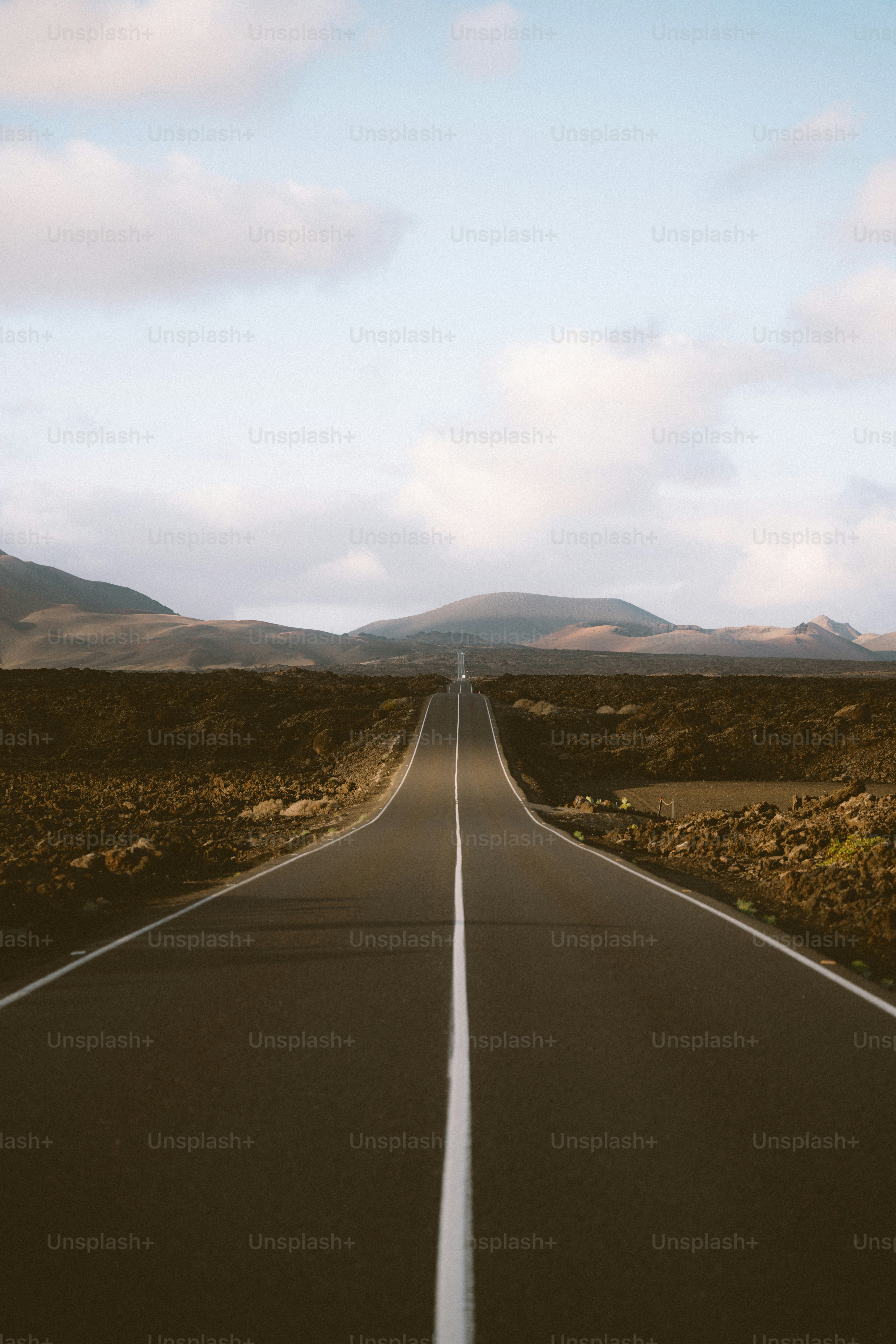Long empty road through volcanic landscape under sky