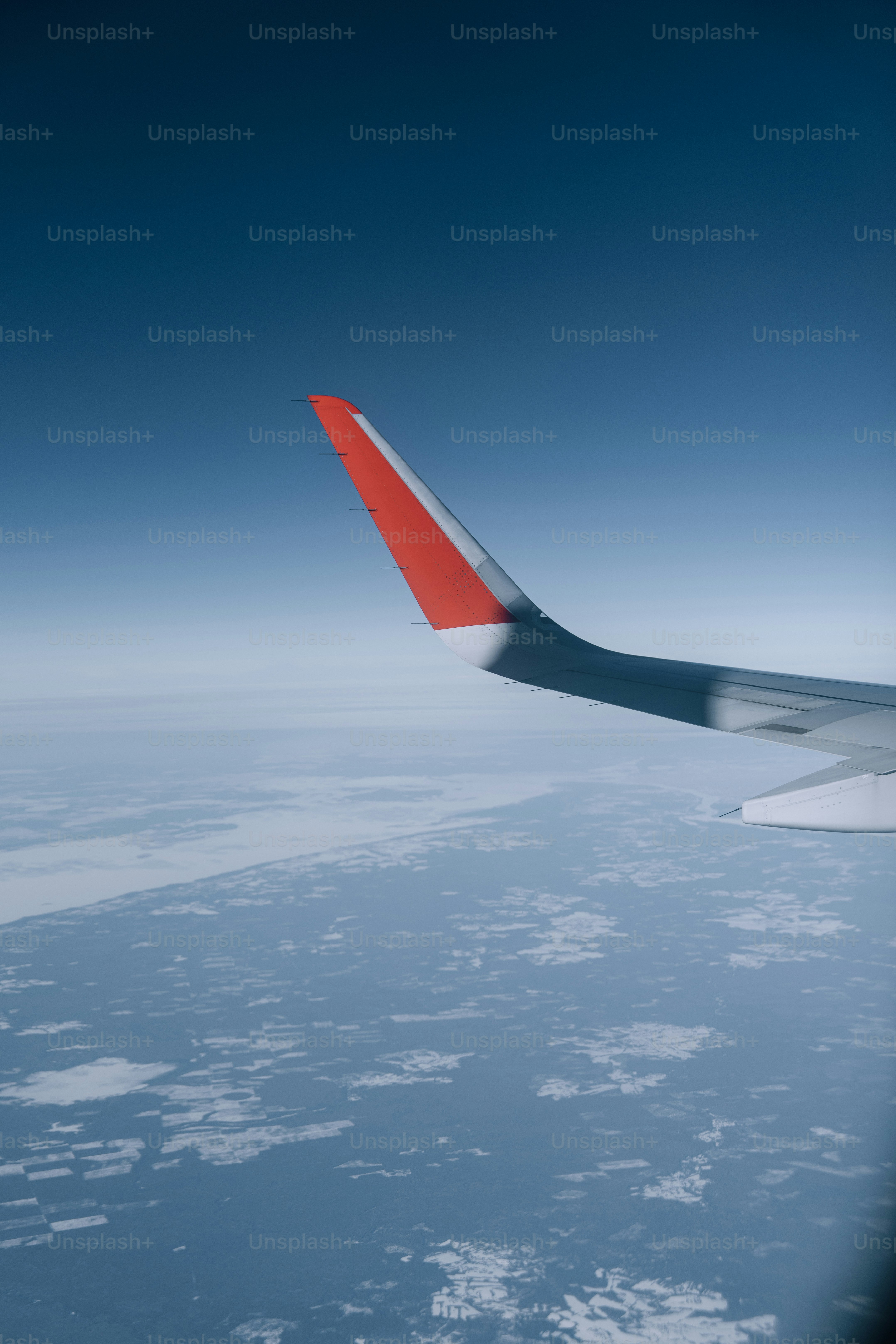 Airplane wing flying over clouds and land.