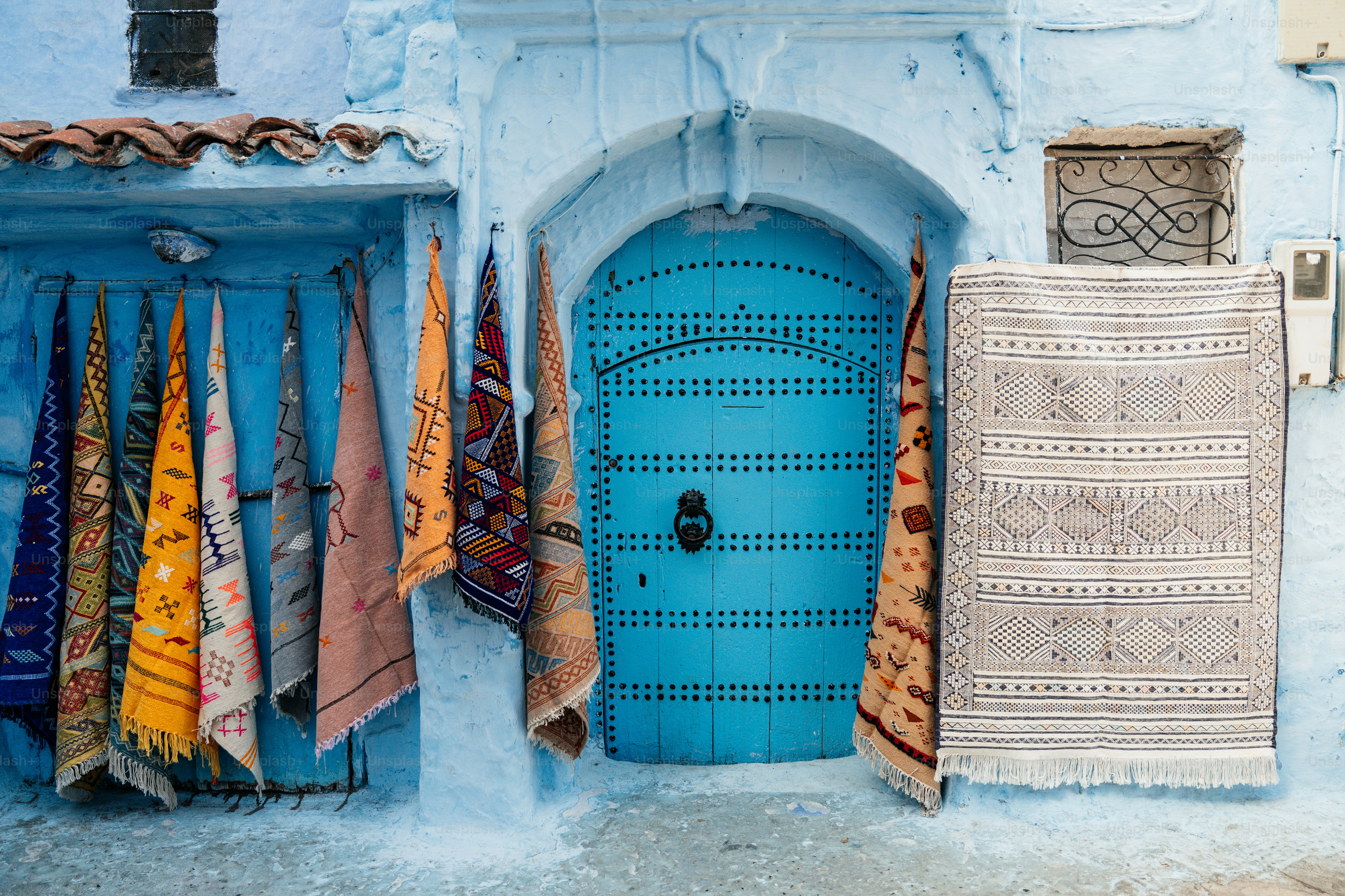 Porta azul com tapetes pendurados em uma cidade marroquina