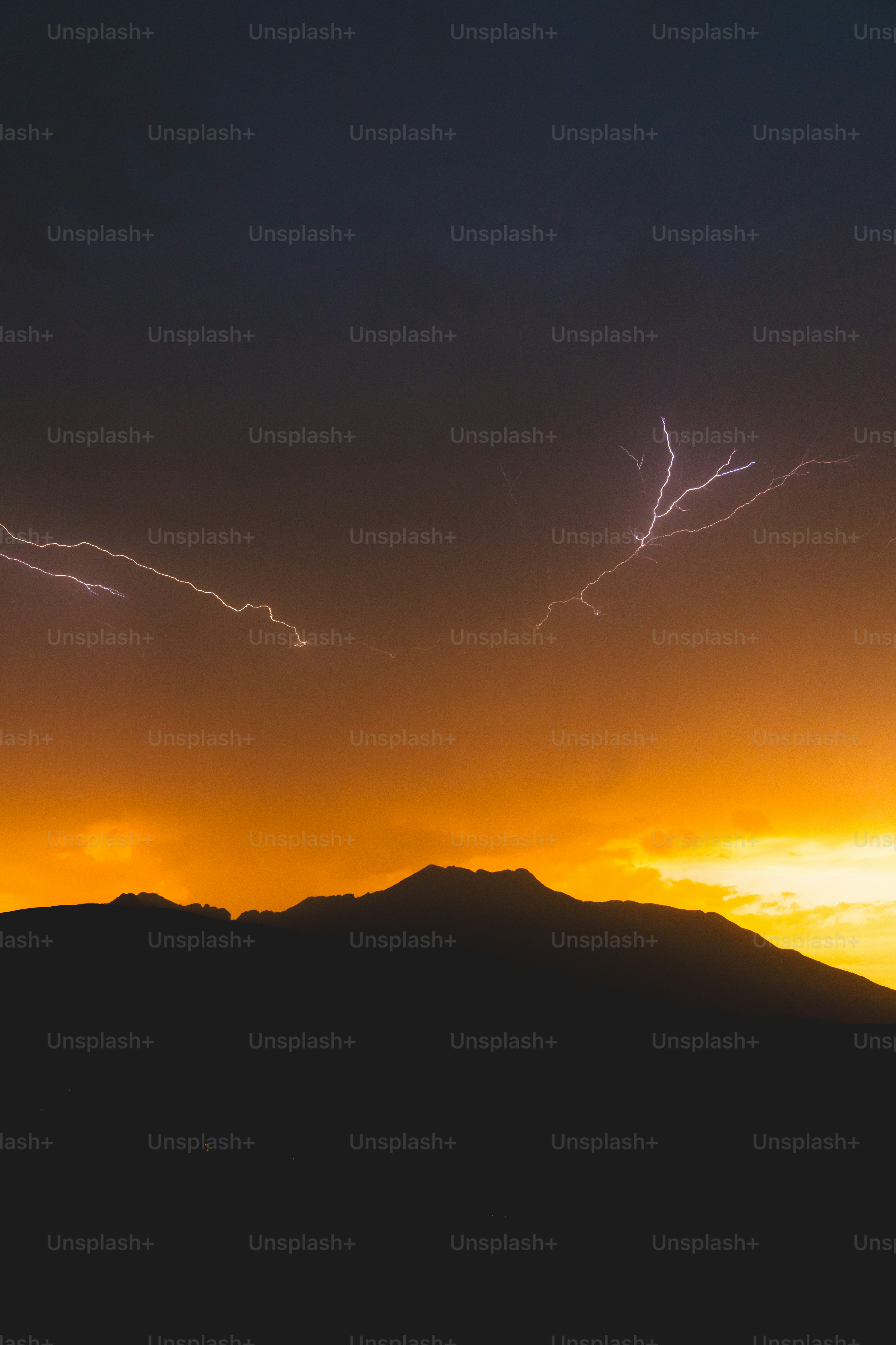 Lightning strikes over a silhouetted mountain at sunset. photo – Night ...