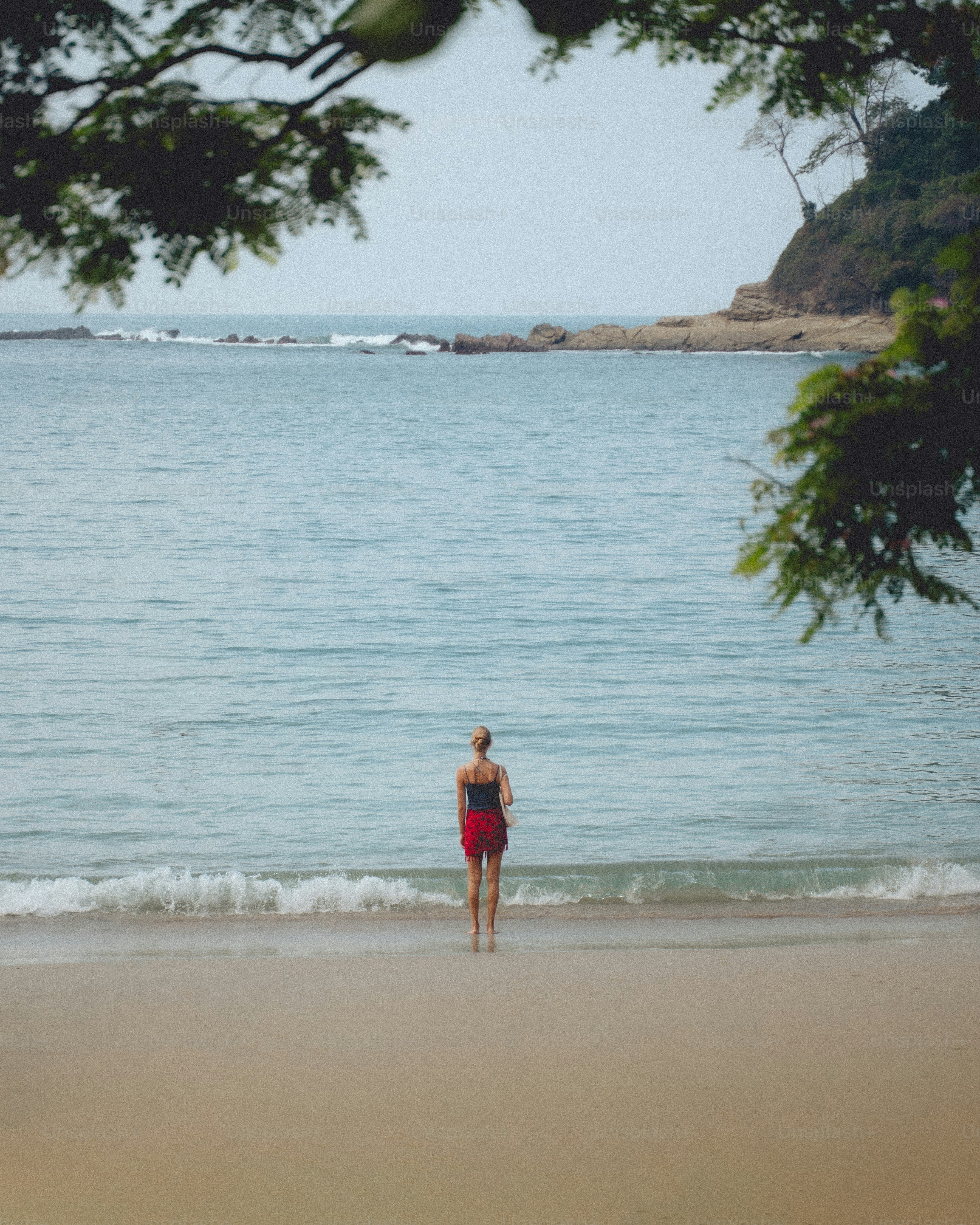 Femme debout sur la plage regardant l’océan