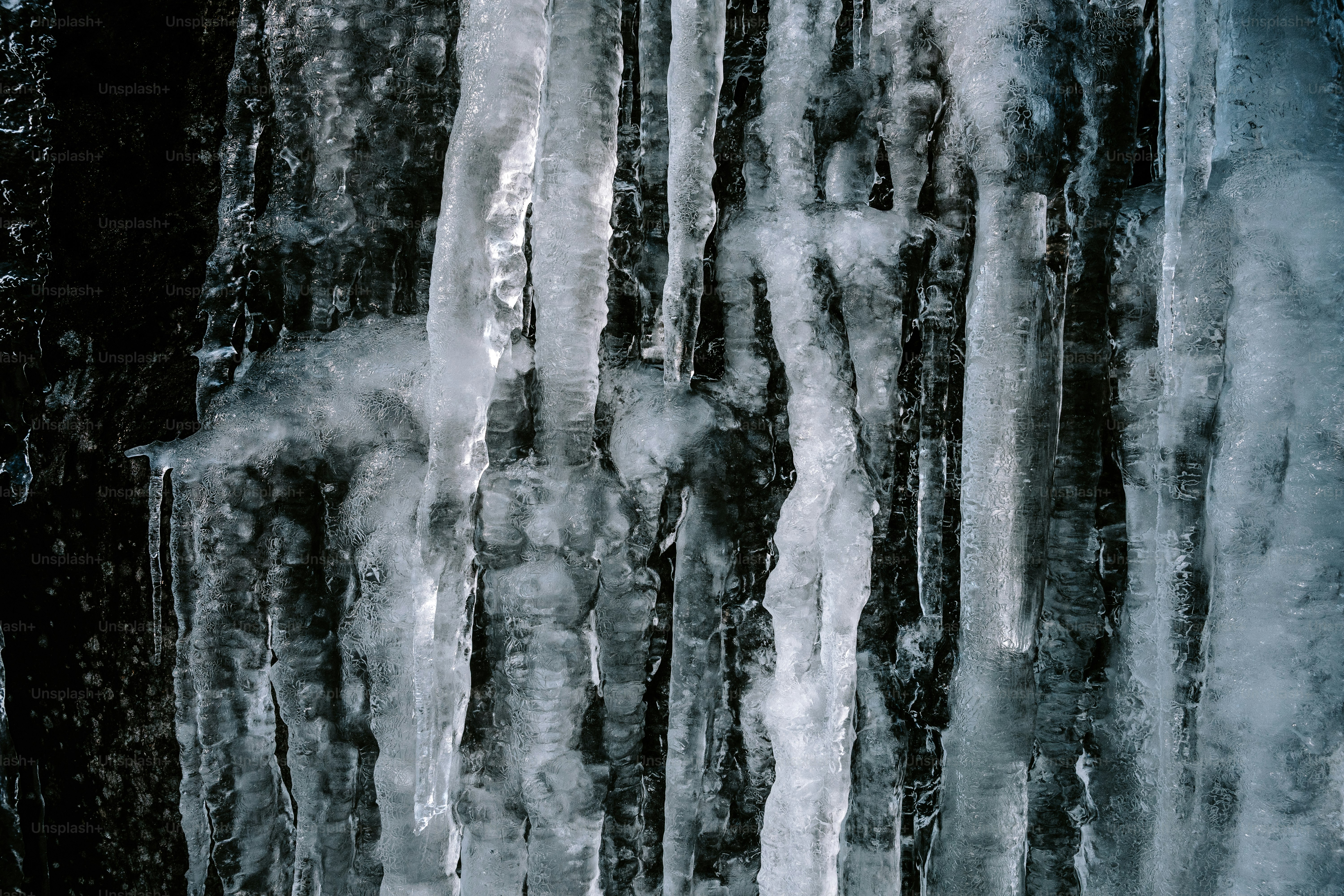 Primer plano de carámbanos colgando de una superficie rocosa y oscura