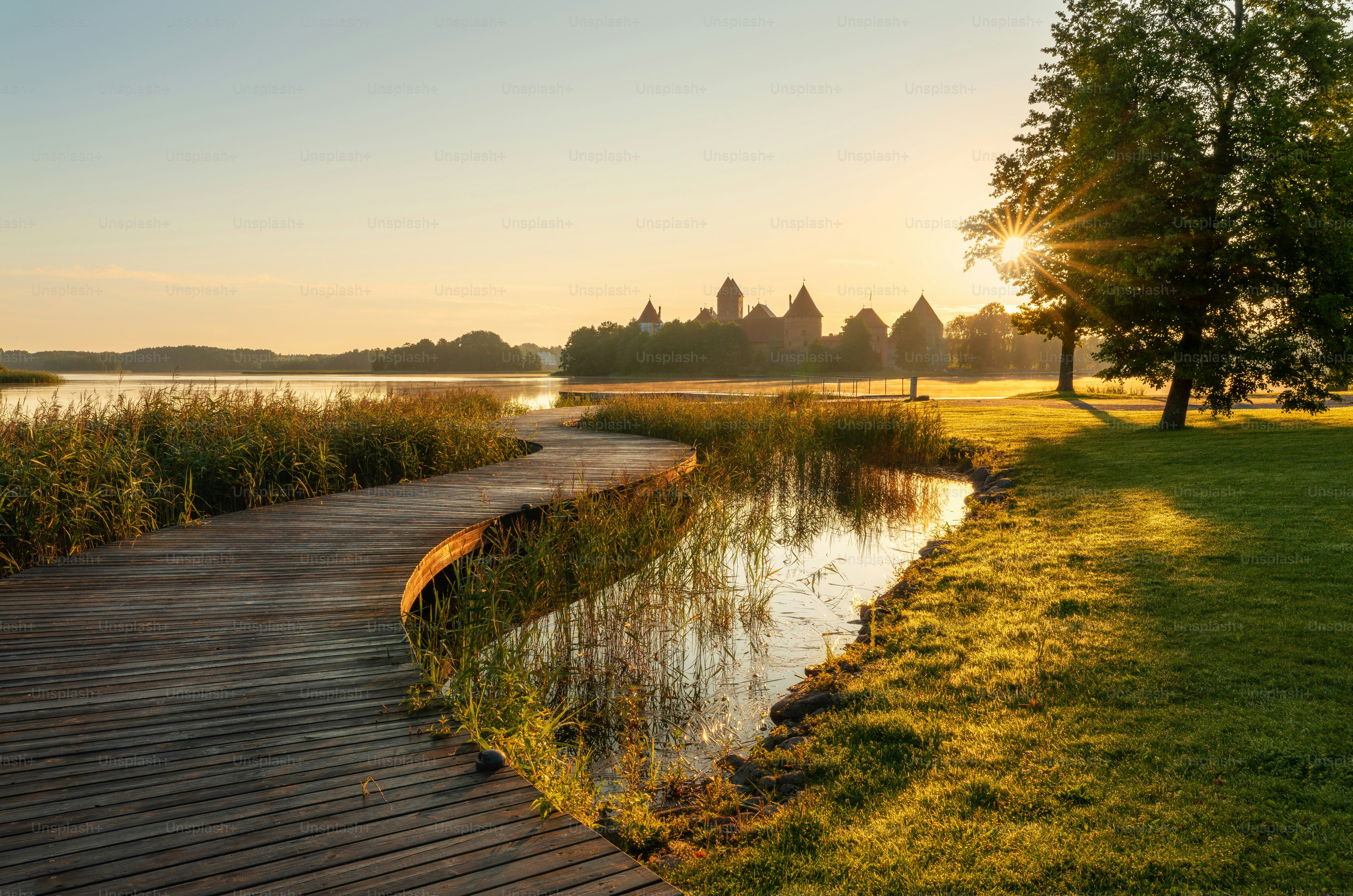 Wooden walkway along a serene lake at sunrise.