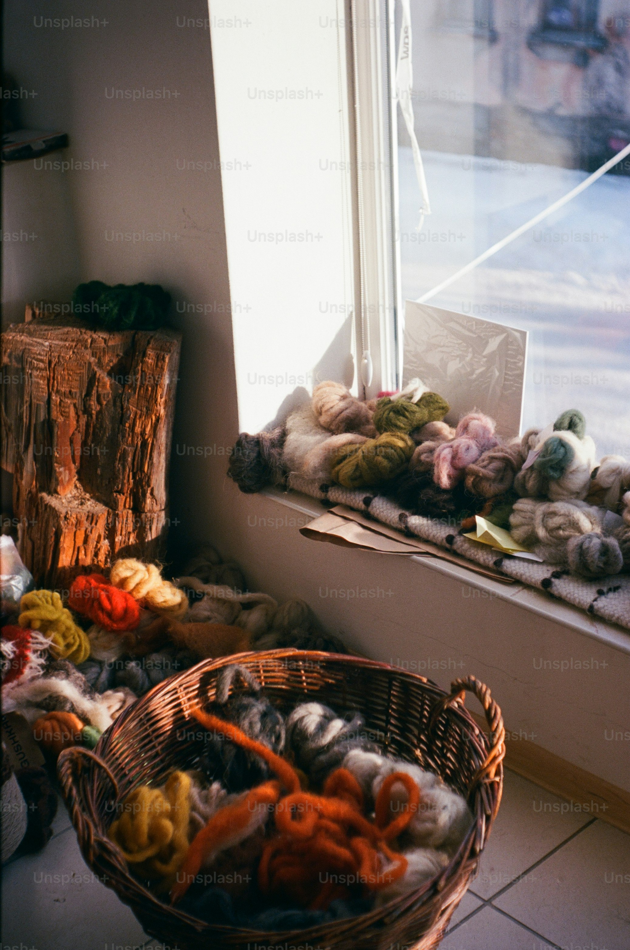 Basket of colorful wool yarns by a sunny window.