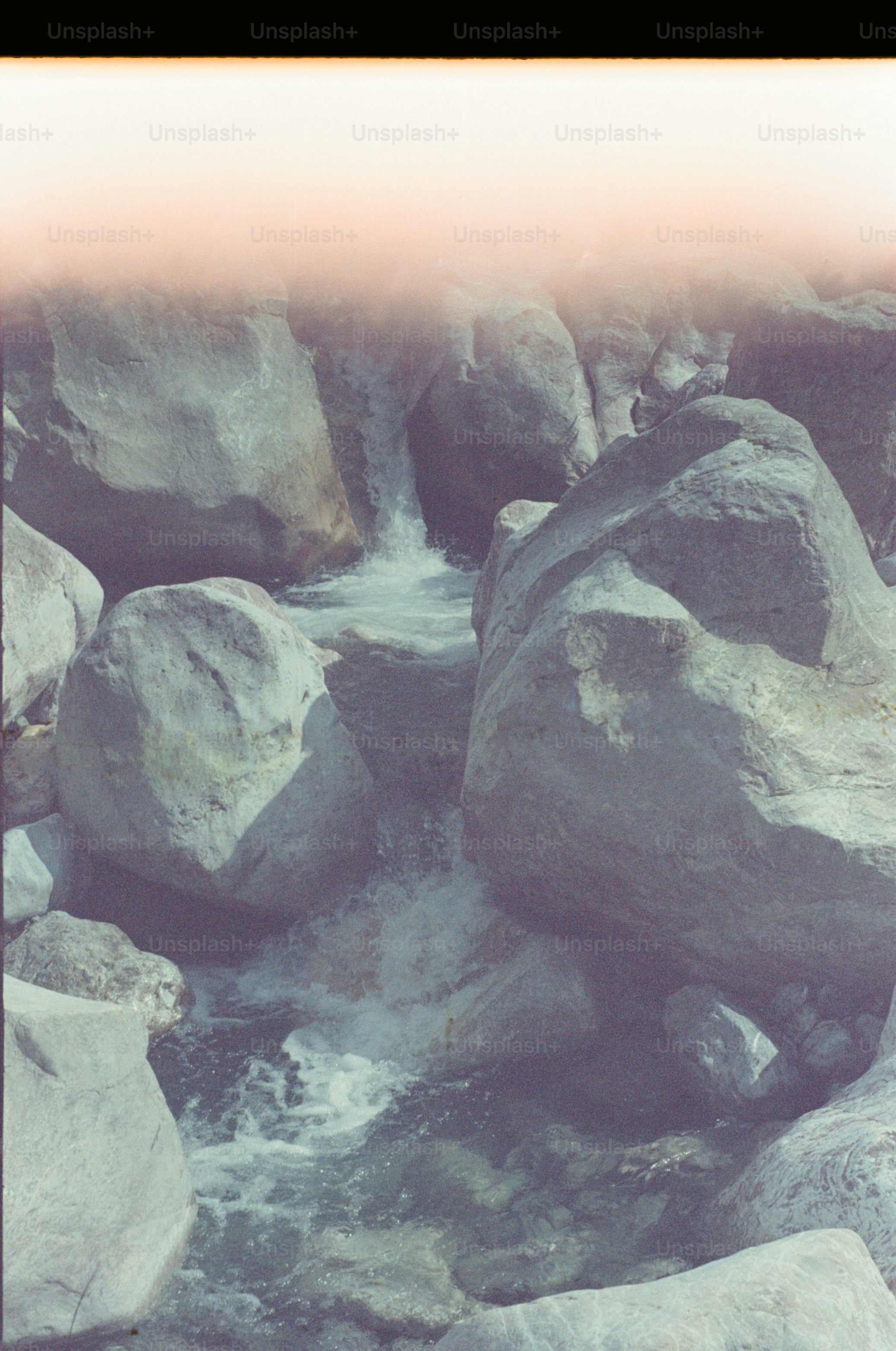 A rocky stream with flowing water and large boulders.