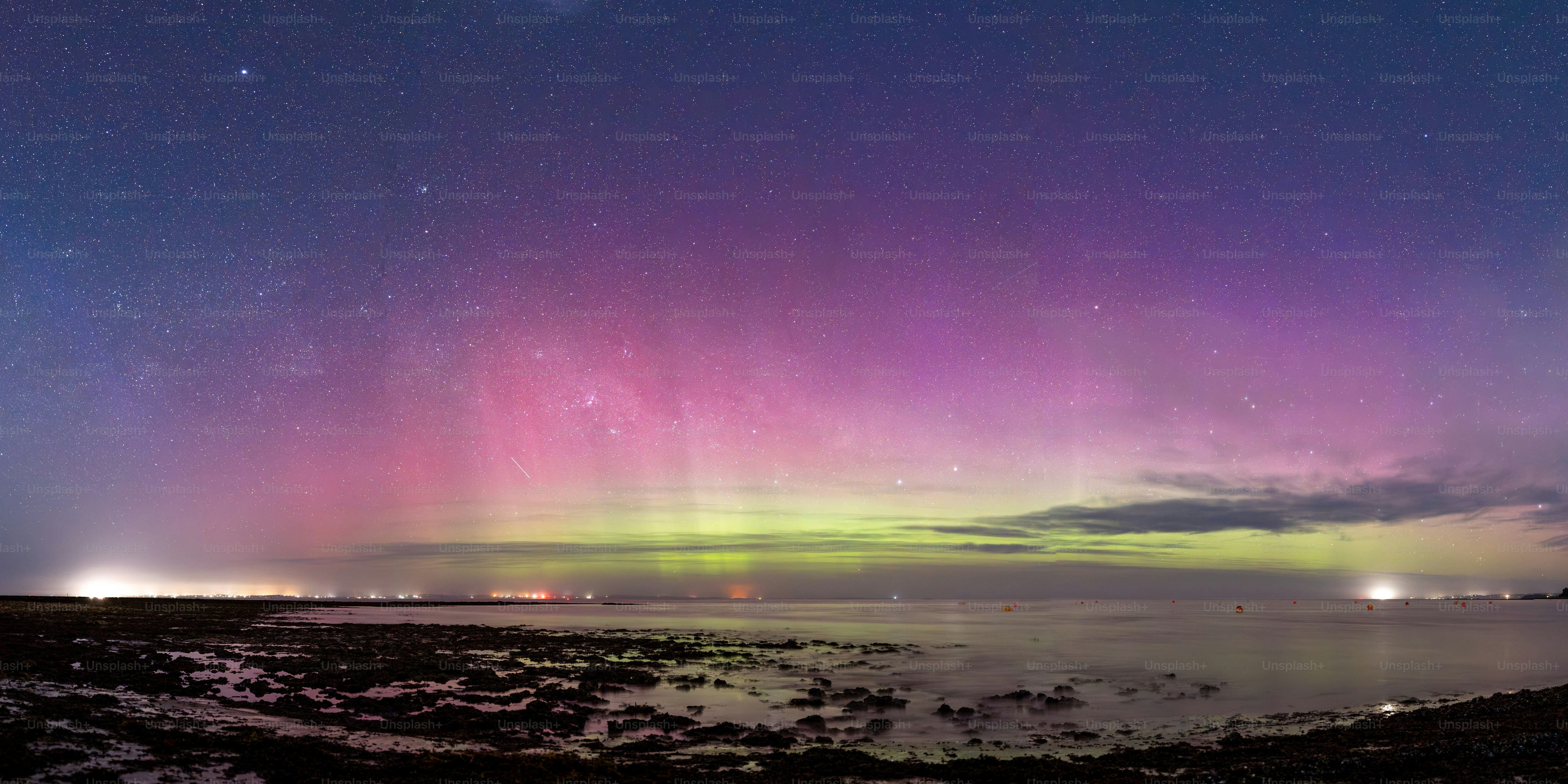 Aurore boréale au-dessus d’un littoral rocheux la nuit.
