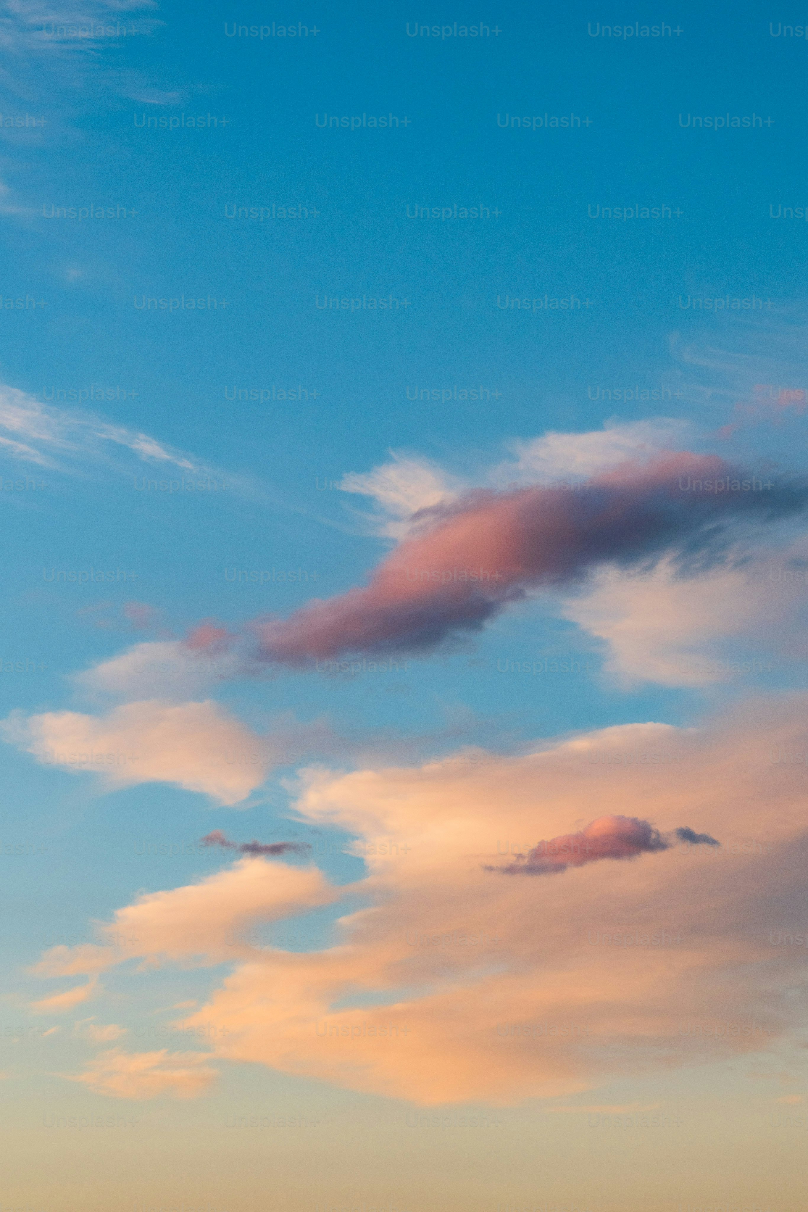 Des nuages roses et orange dans un ciel bleu.