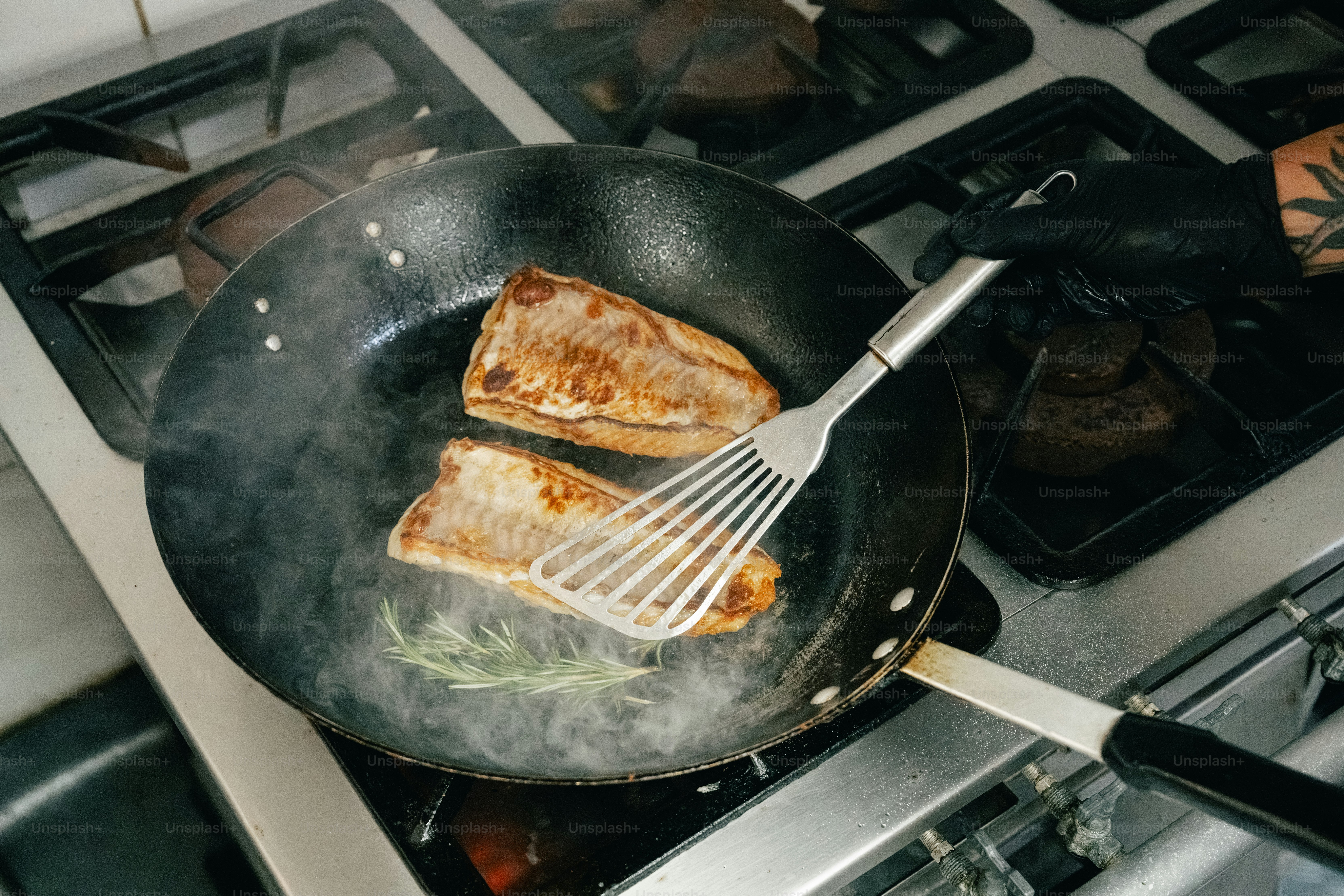 Two fish fillets cooking in a pan