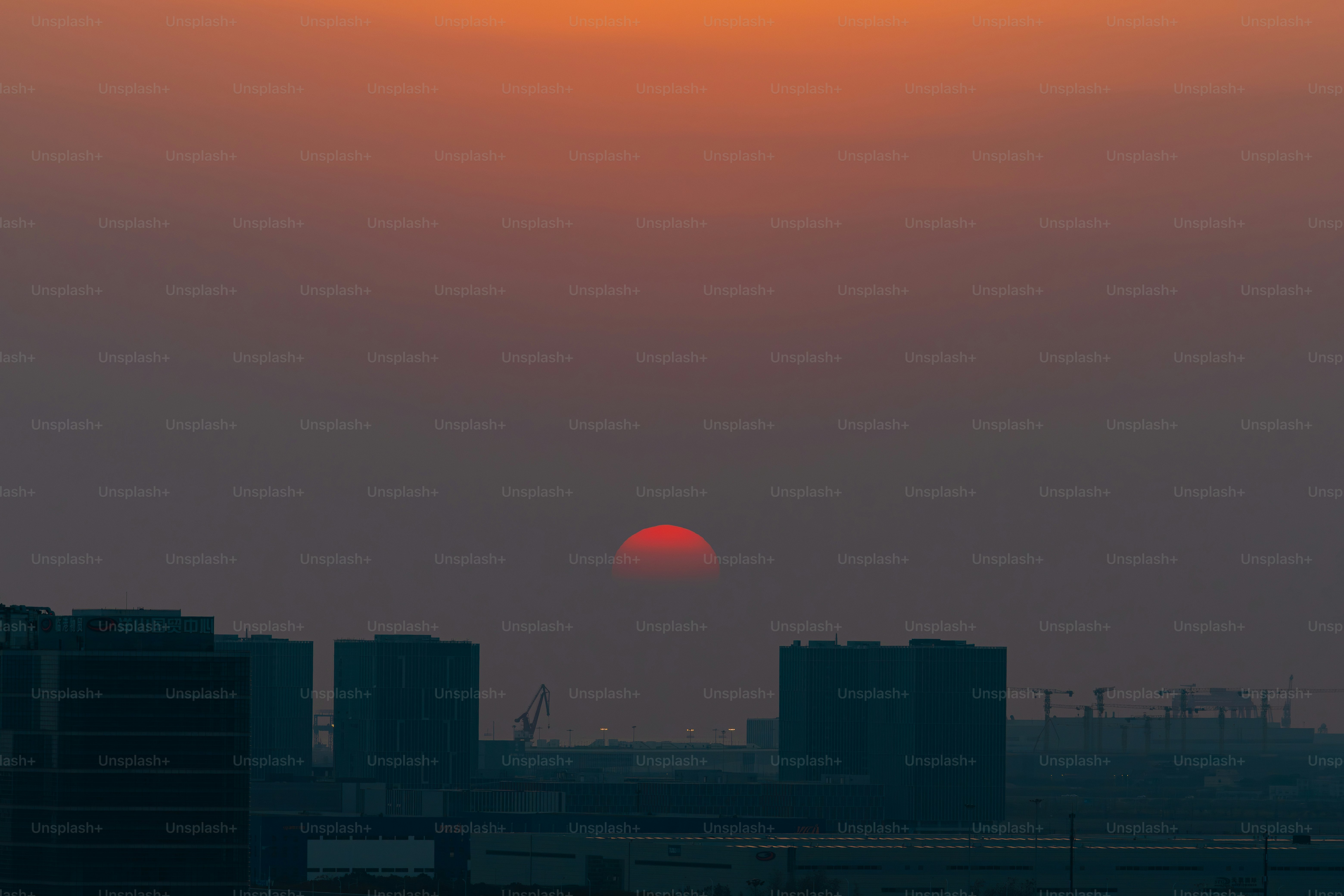 Red sun setting over city skyline at dusk