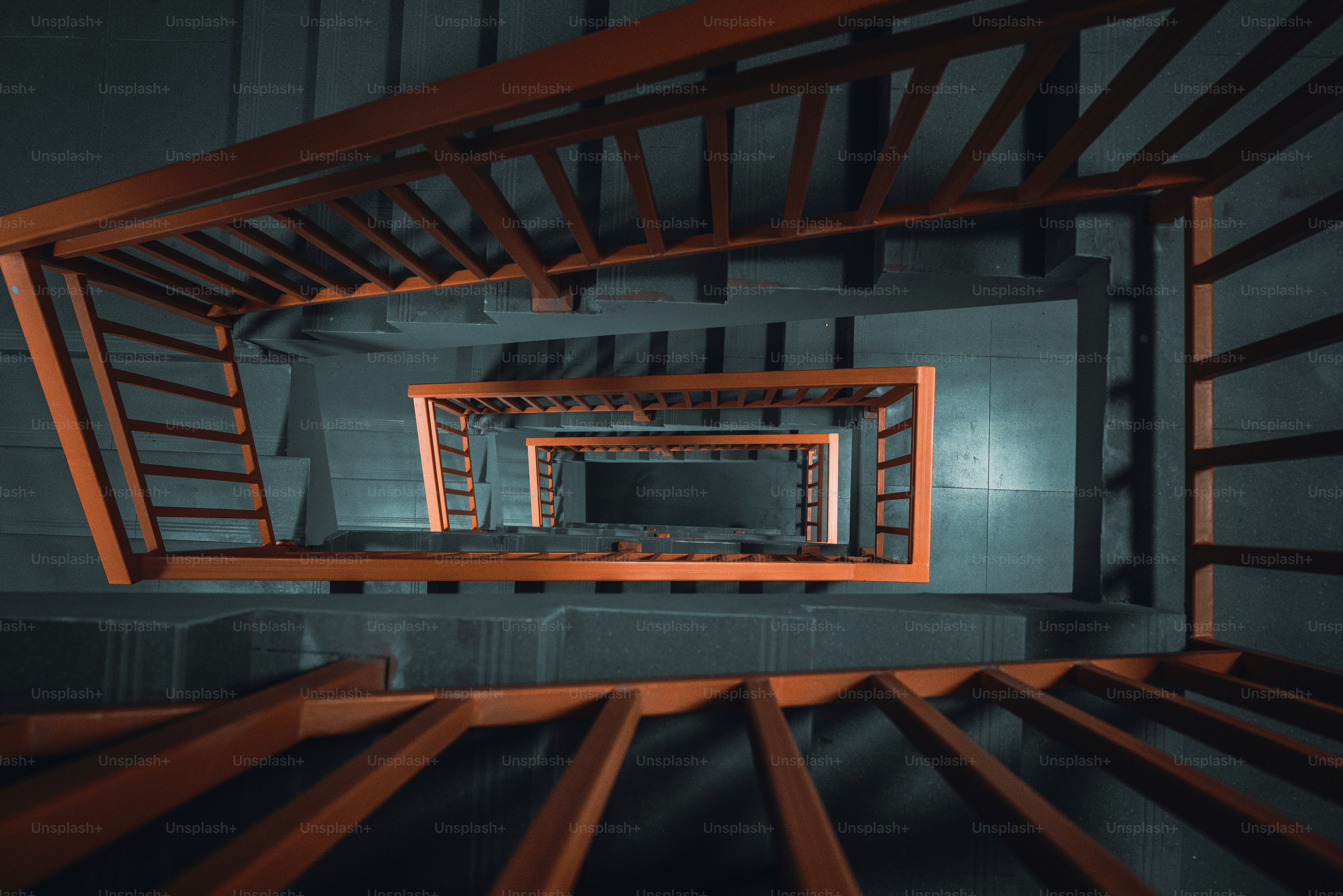 Looking down a red spiral staircase into darkness