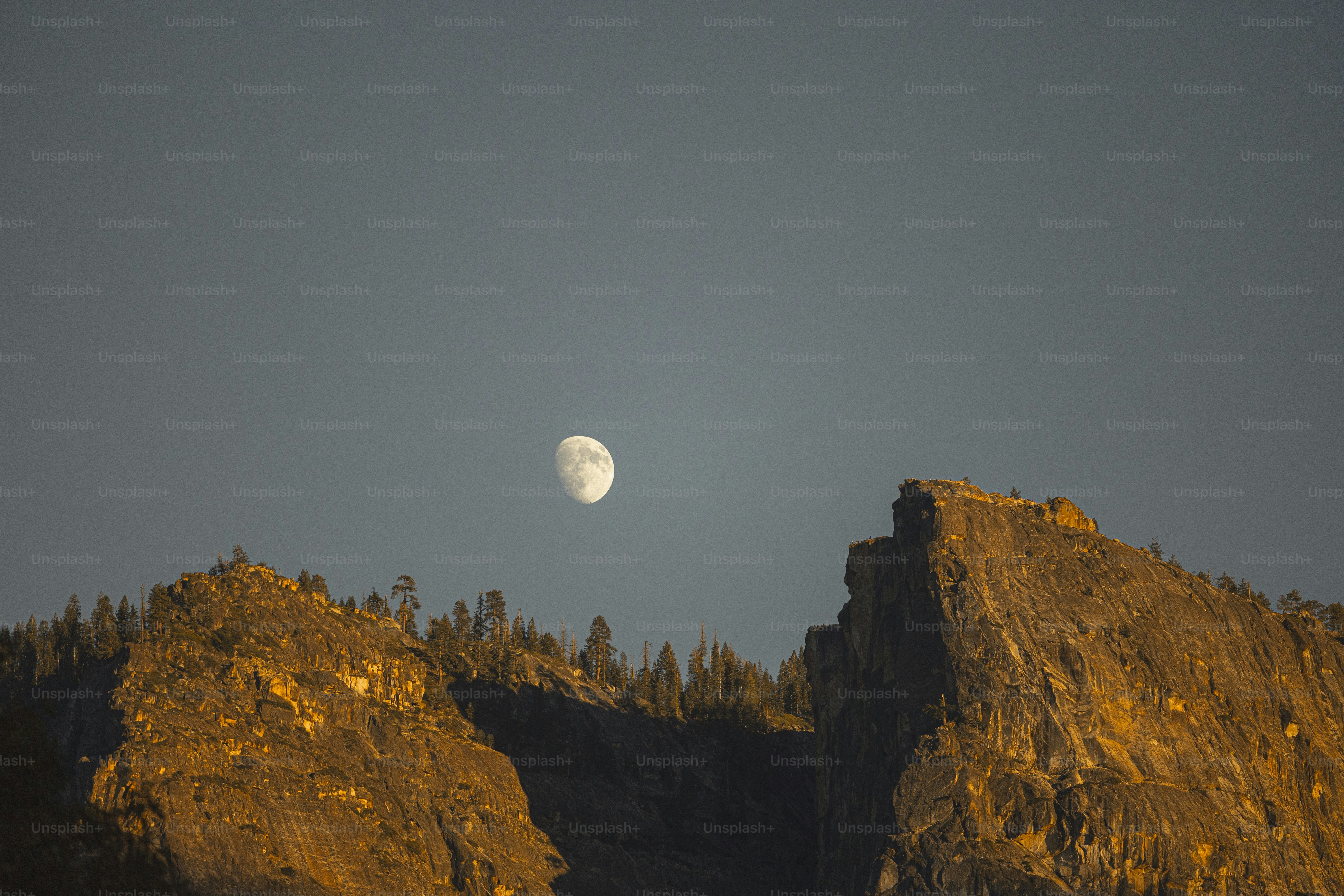 Full moon over rocky mountain peaks at sunset