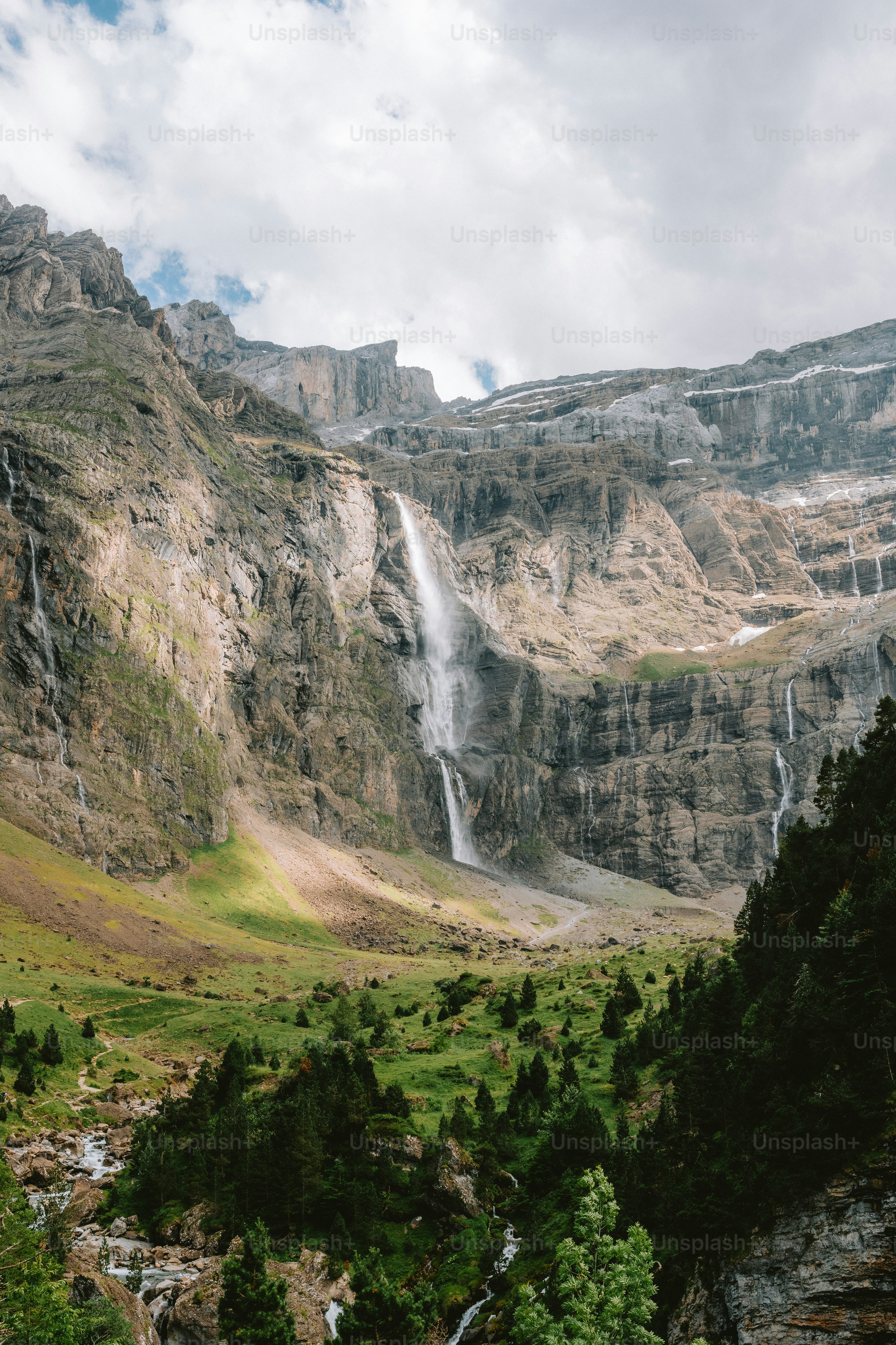 Altas cascadas caen por una pared rocosa de montaña.