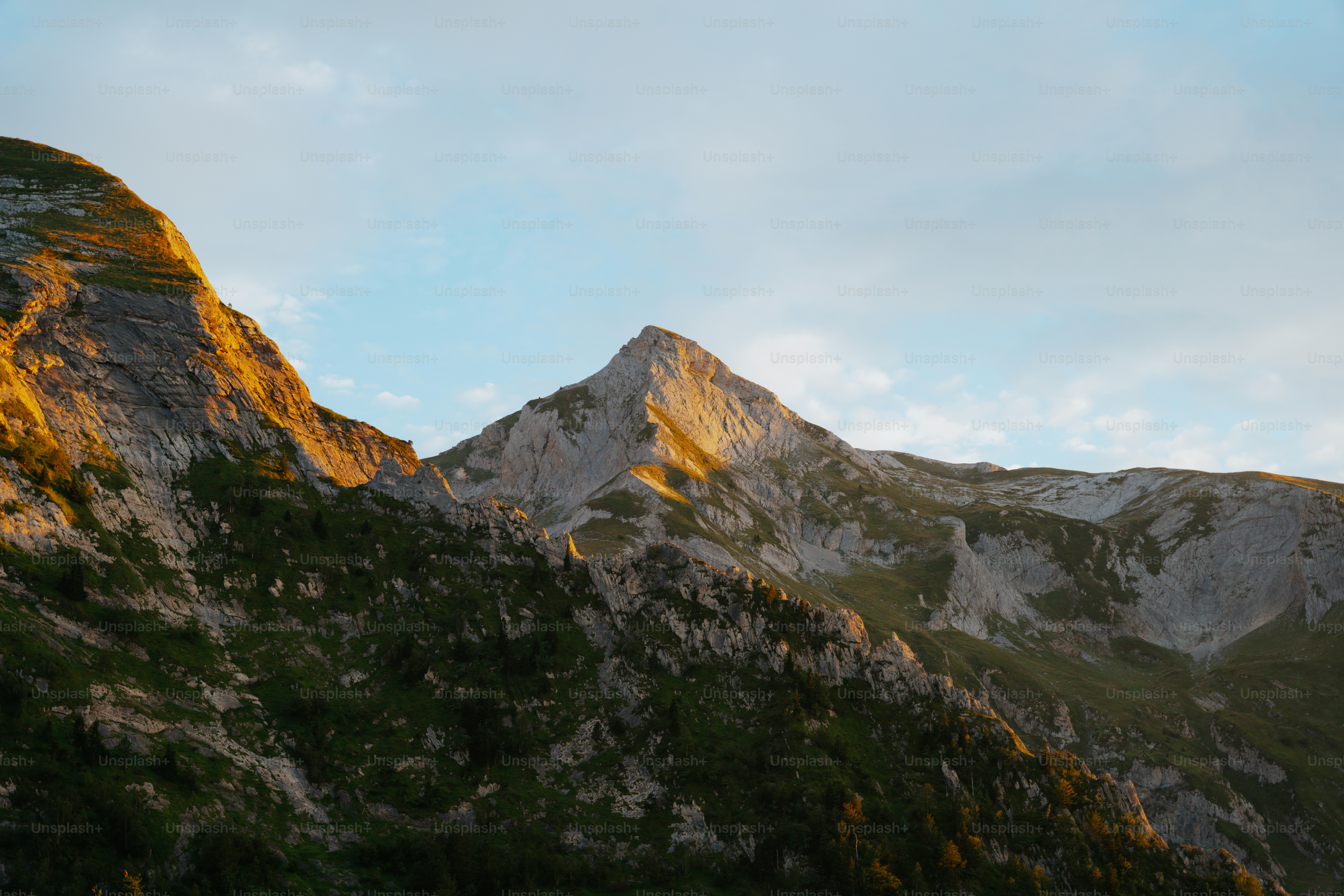 La luz del sol ilumina las cumbres montañosas escarpadas bajo un cielo despejado.