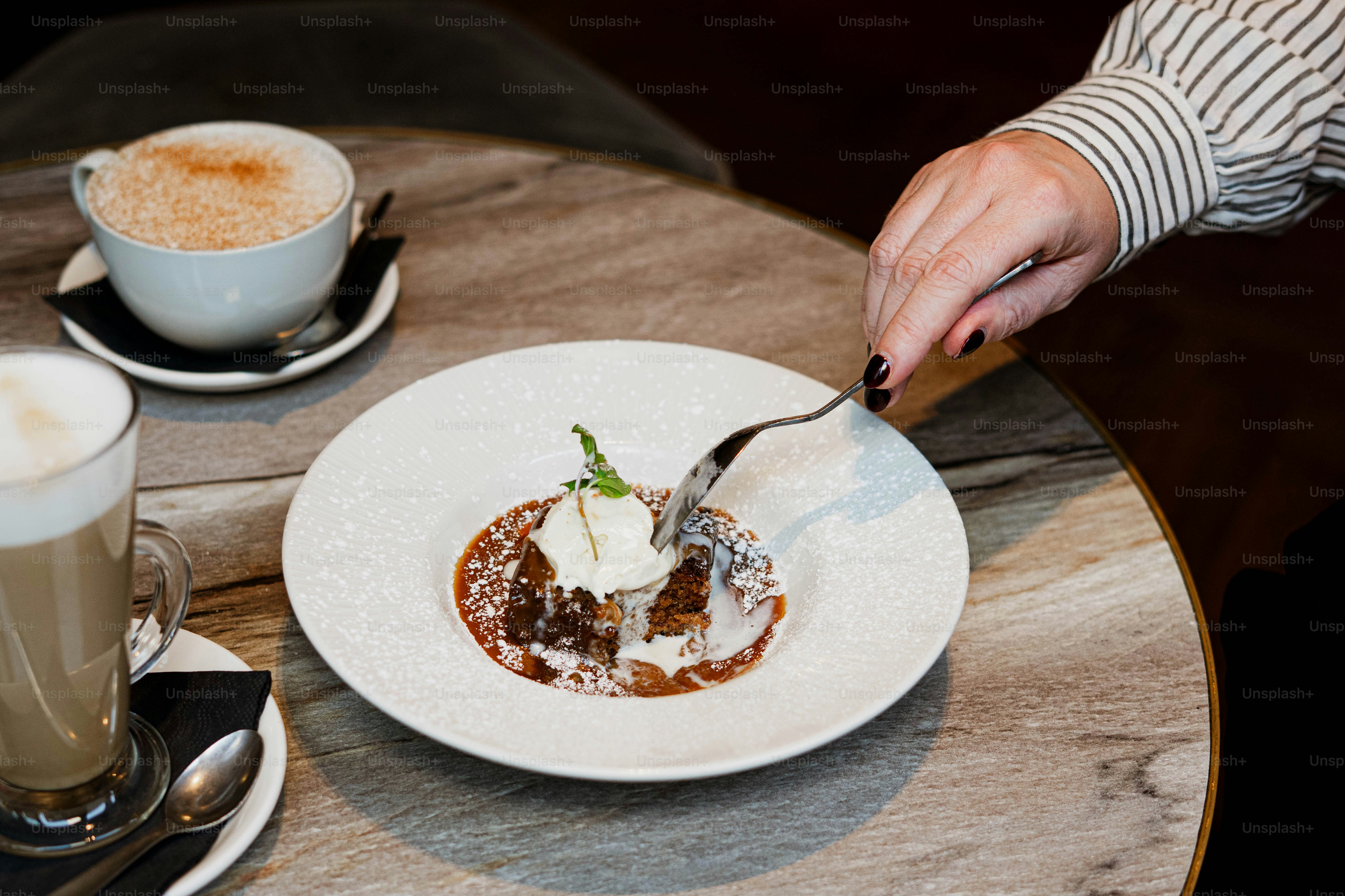 Person eating dessert with coffee on table