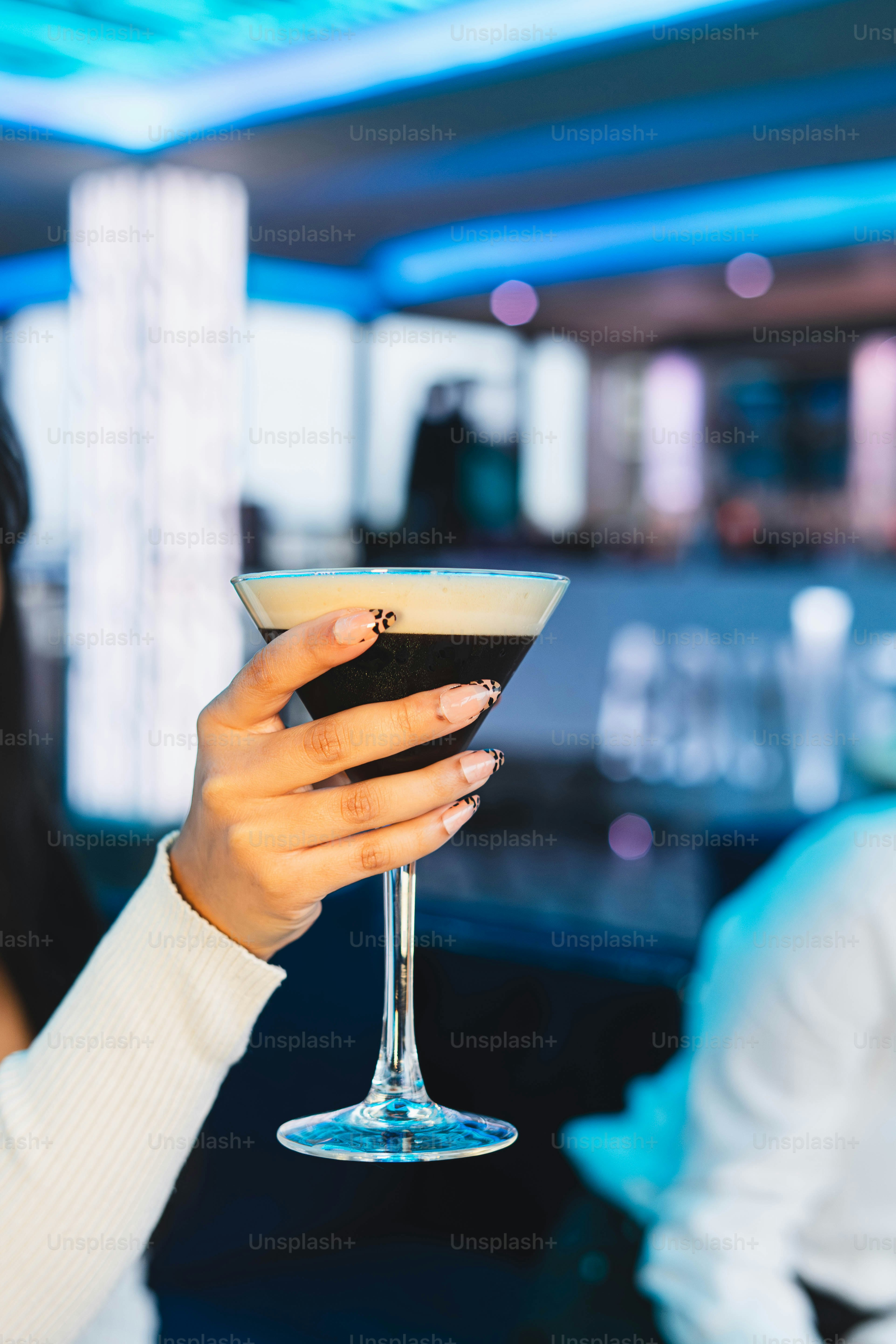 Woman holding a dark cocktail in a martini glass