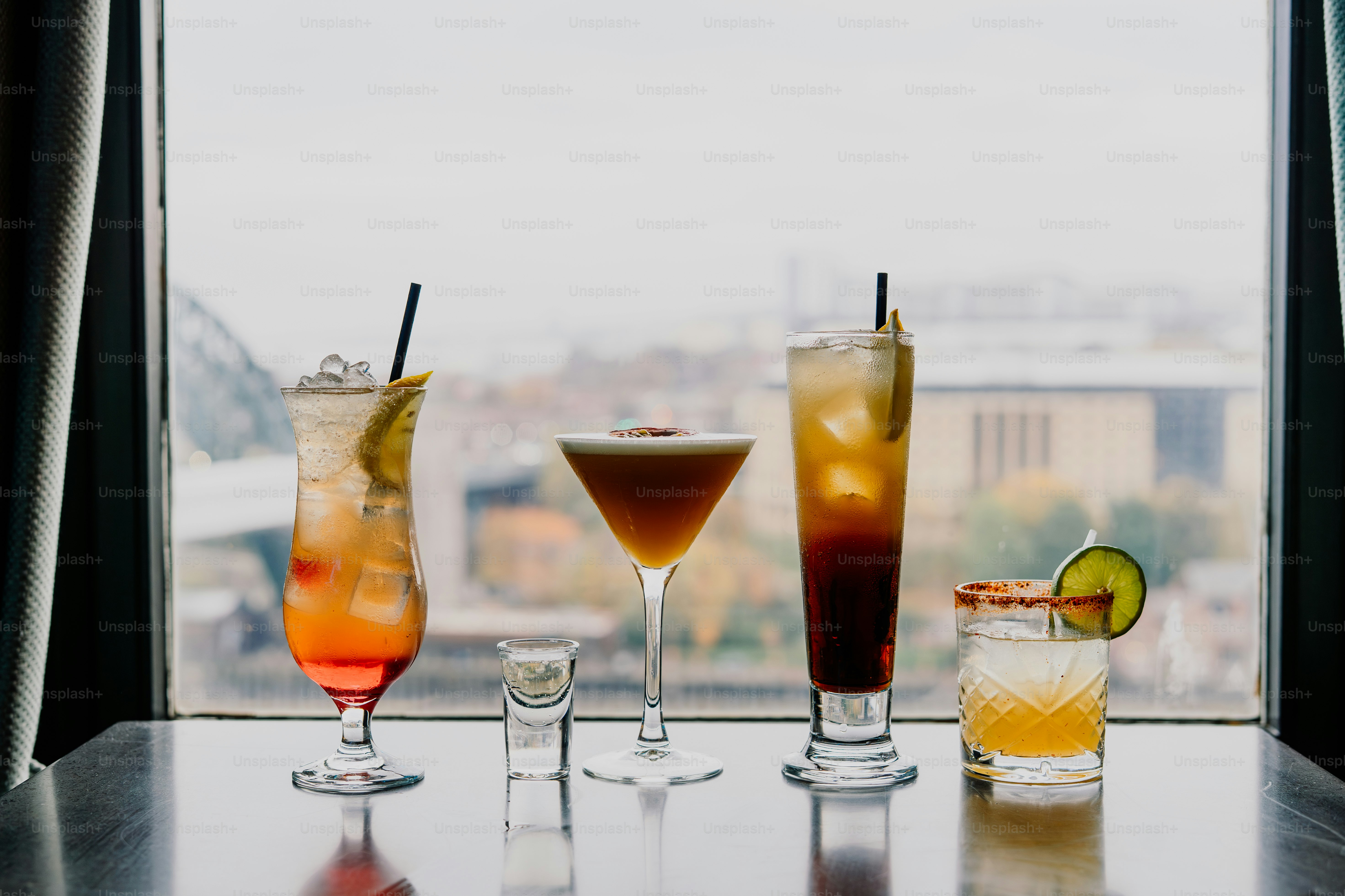 Four colorful cocktails arranged by a window.