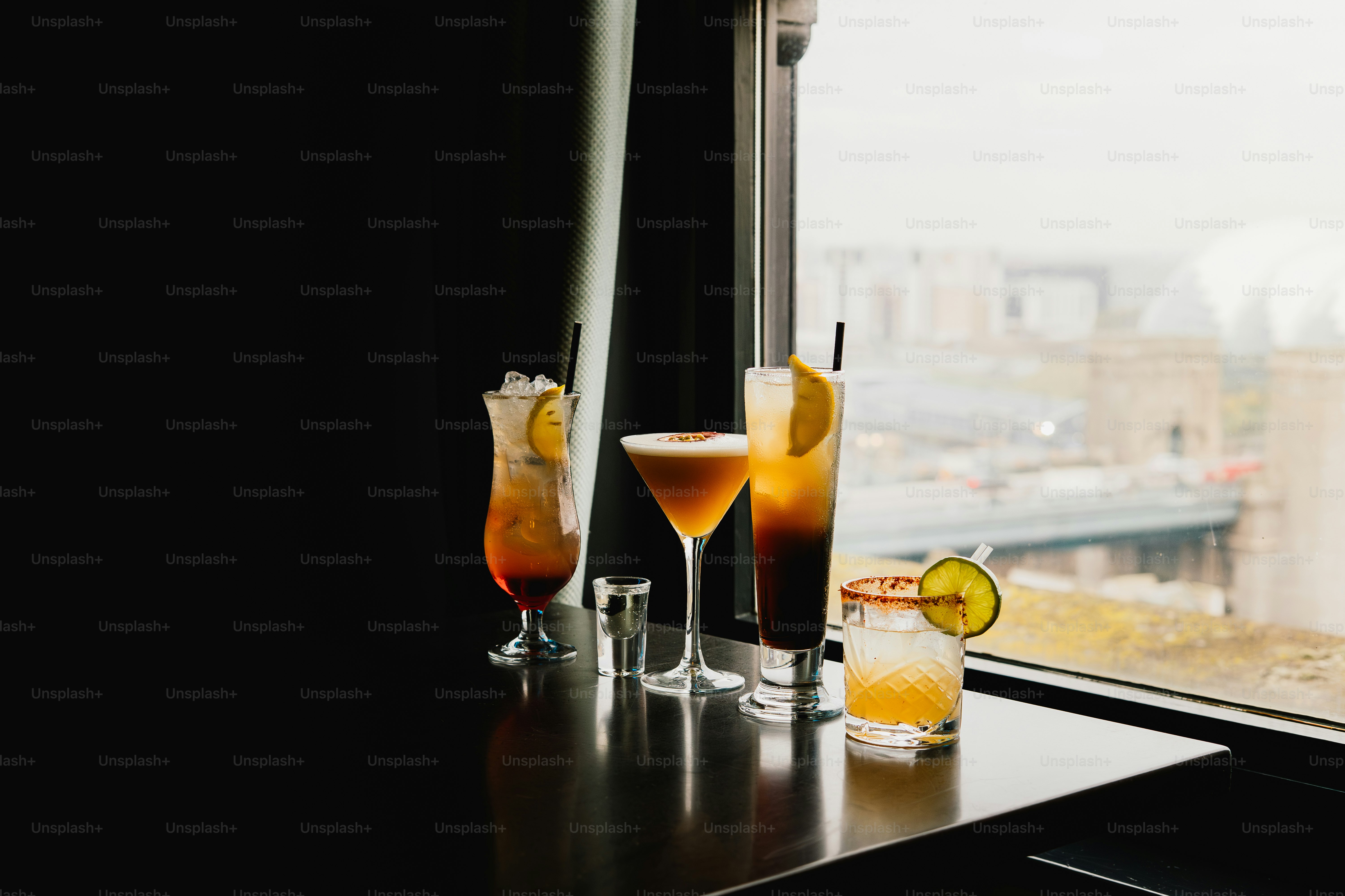 Four cocktails on a table by the window.