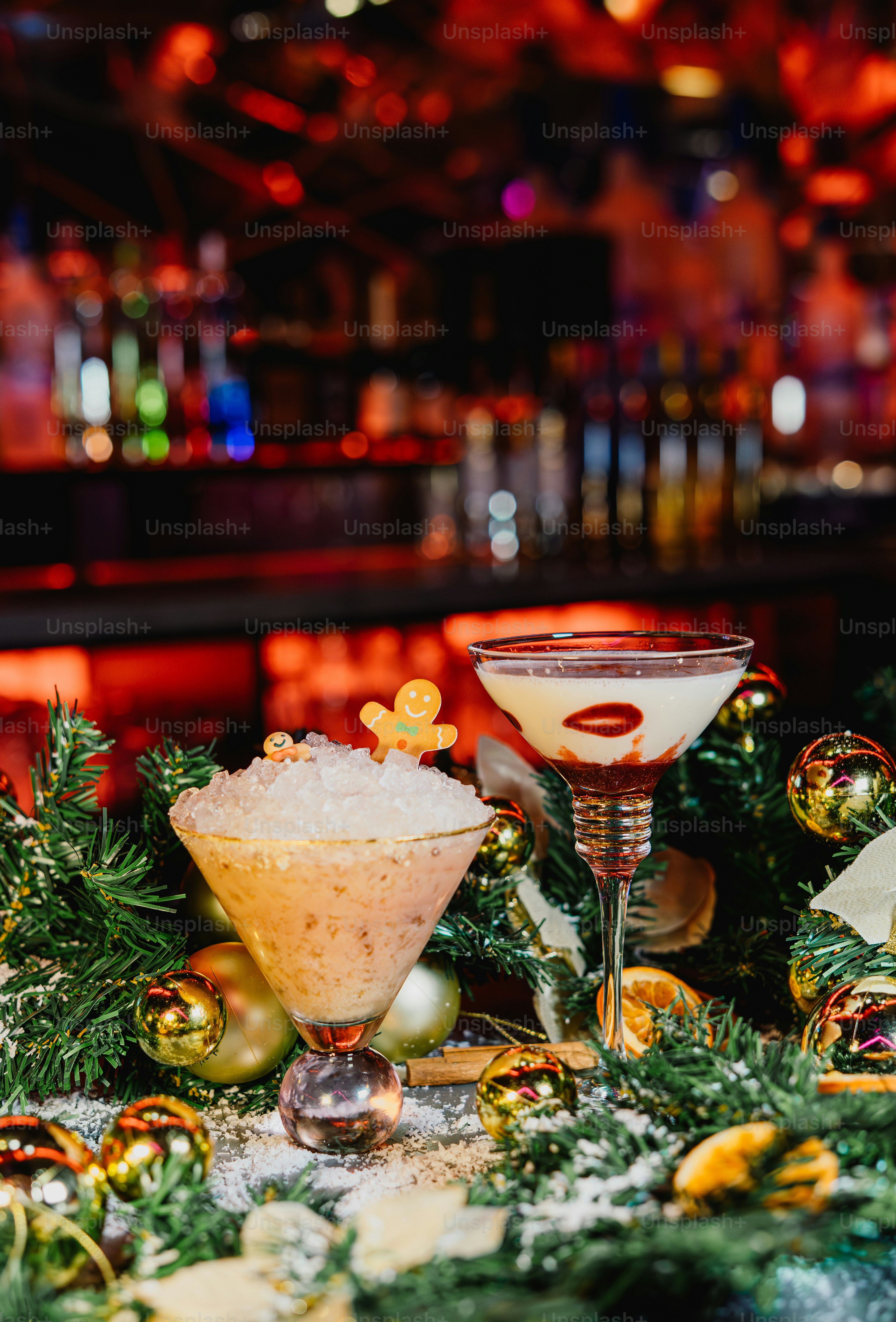 Two festive holiday cocktails decorated with gingerbread and berries