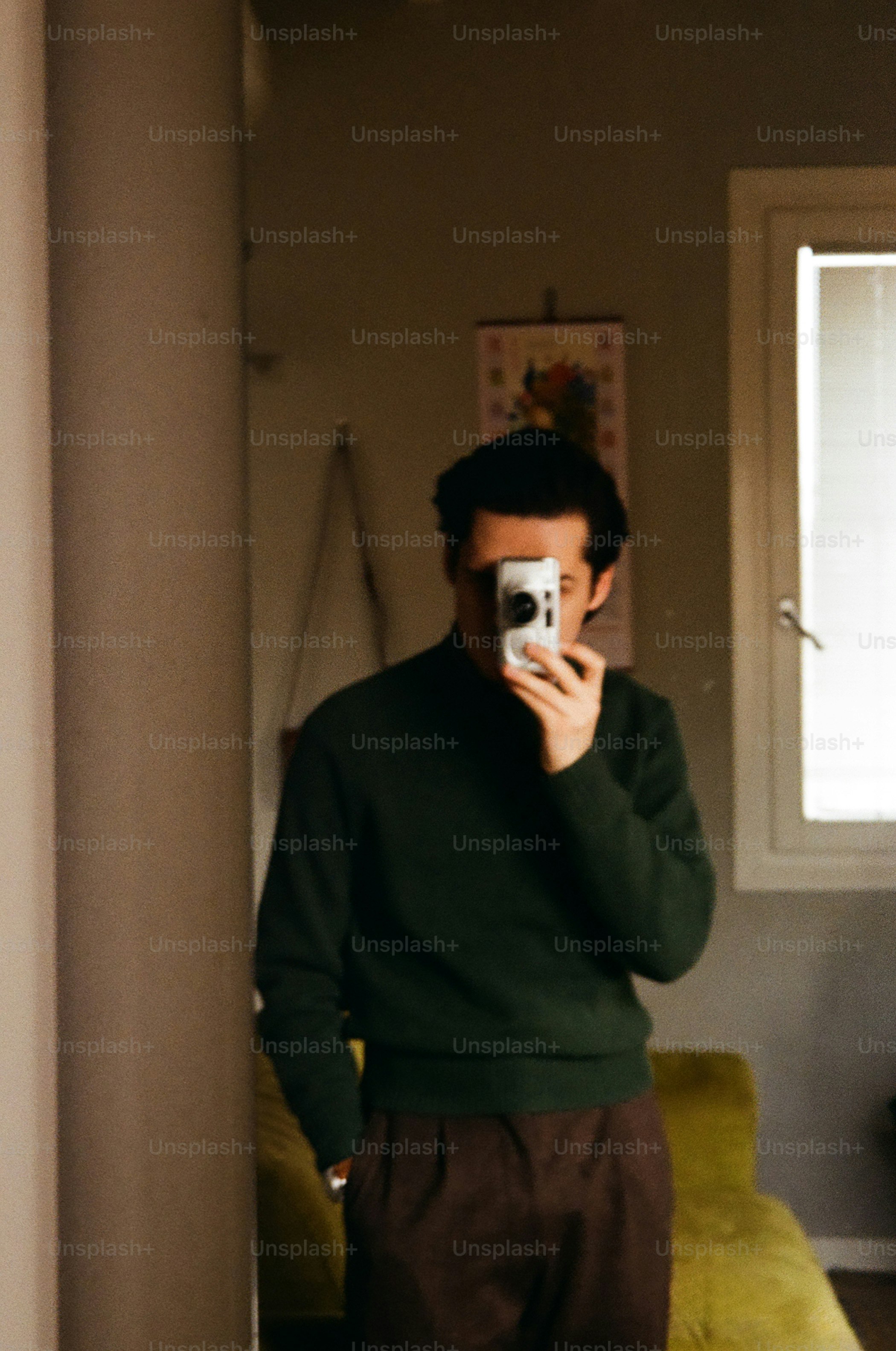 Mann im grünen Pullover macht ein Selfie mit der Kamera.