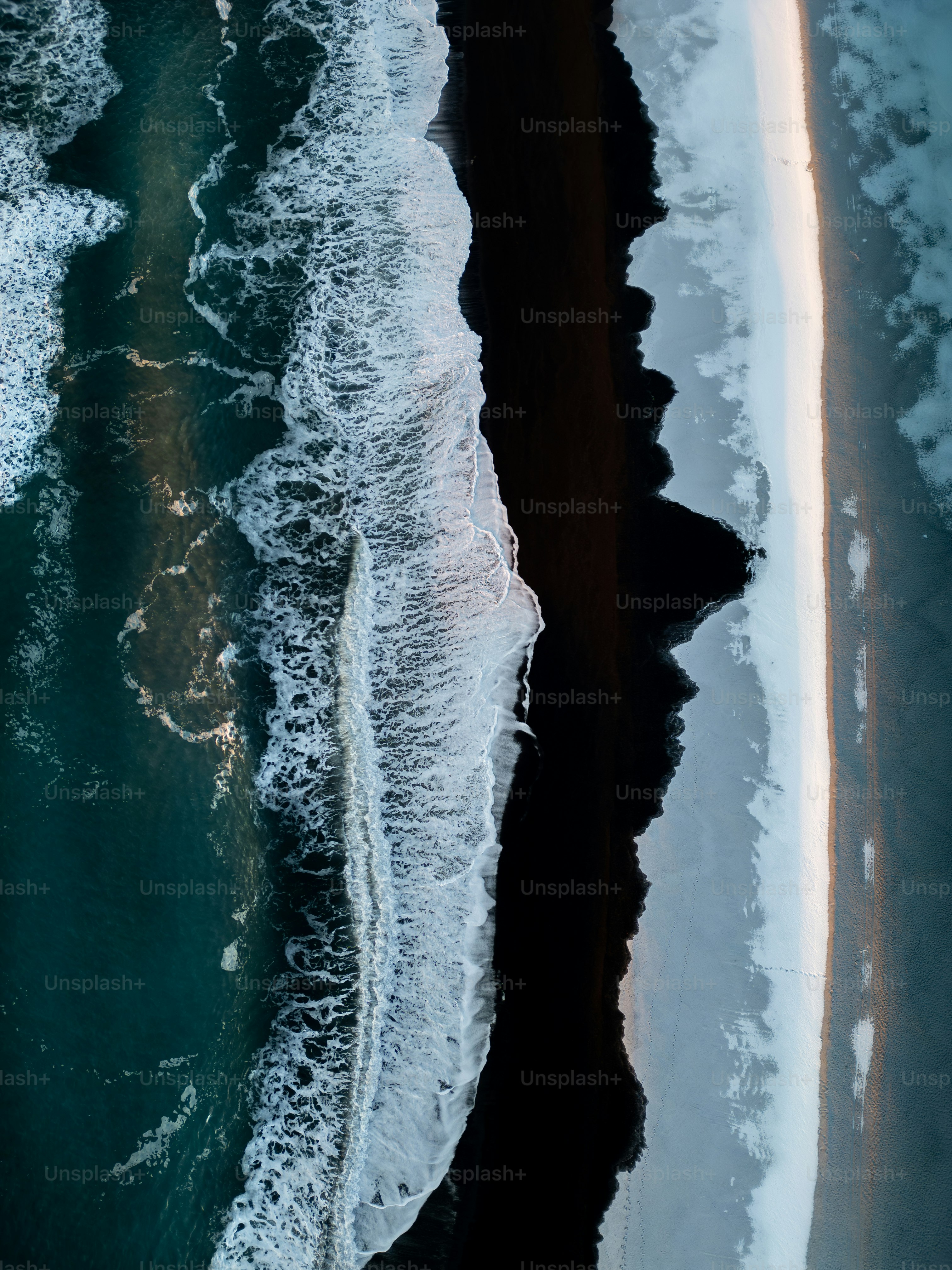 Aerial view of waves crashing on a dark sandy beach