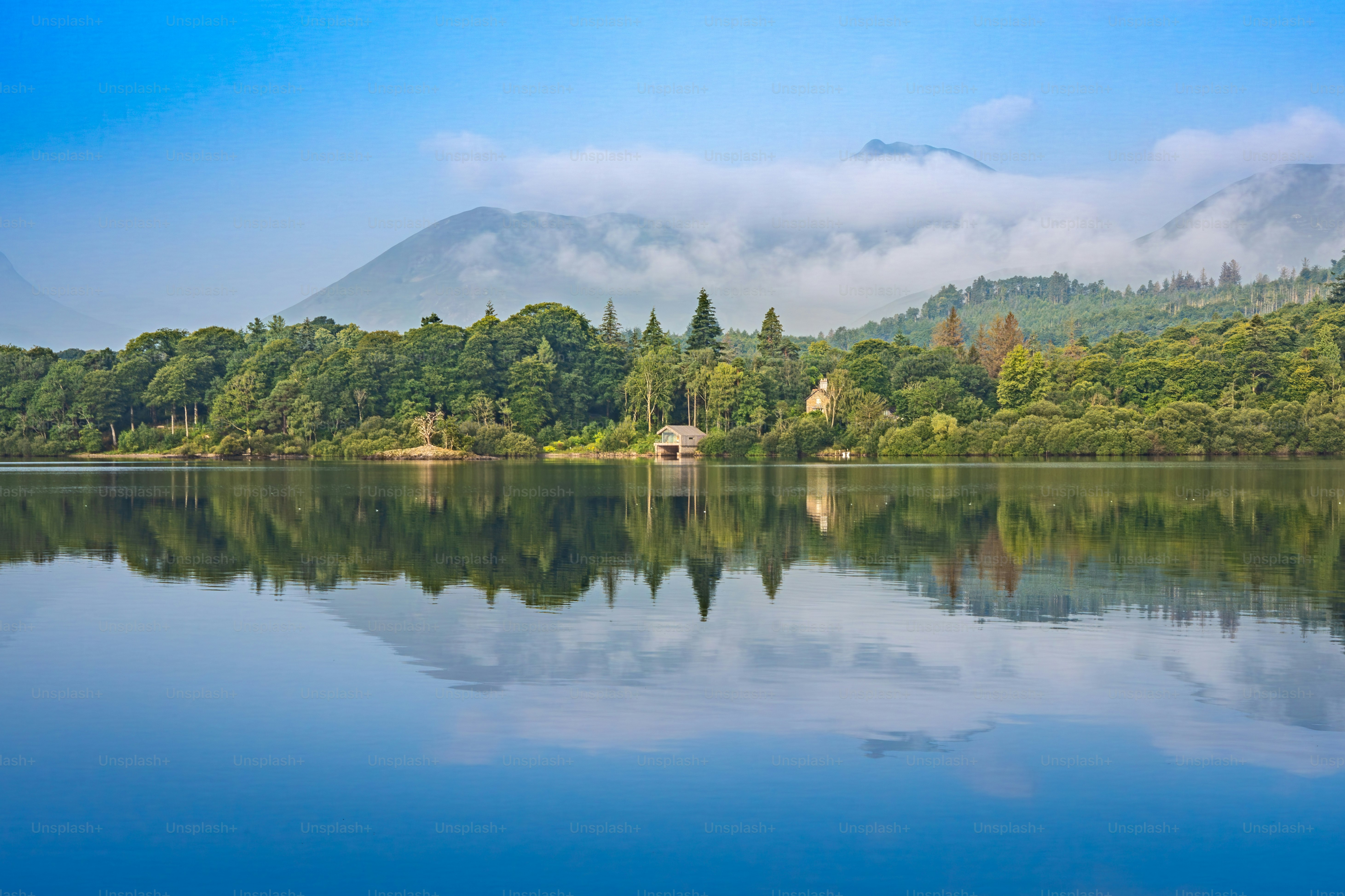 Ein ruhiger See, der üppig grüne Bäume und ferne Berge widerspiegelt.