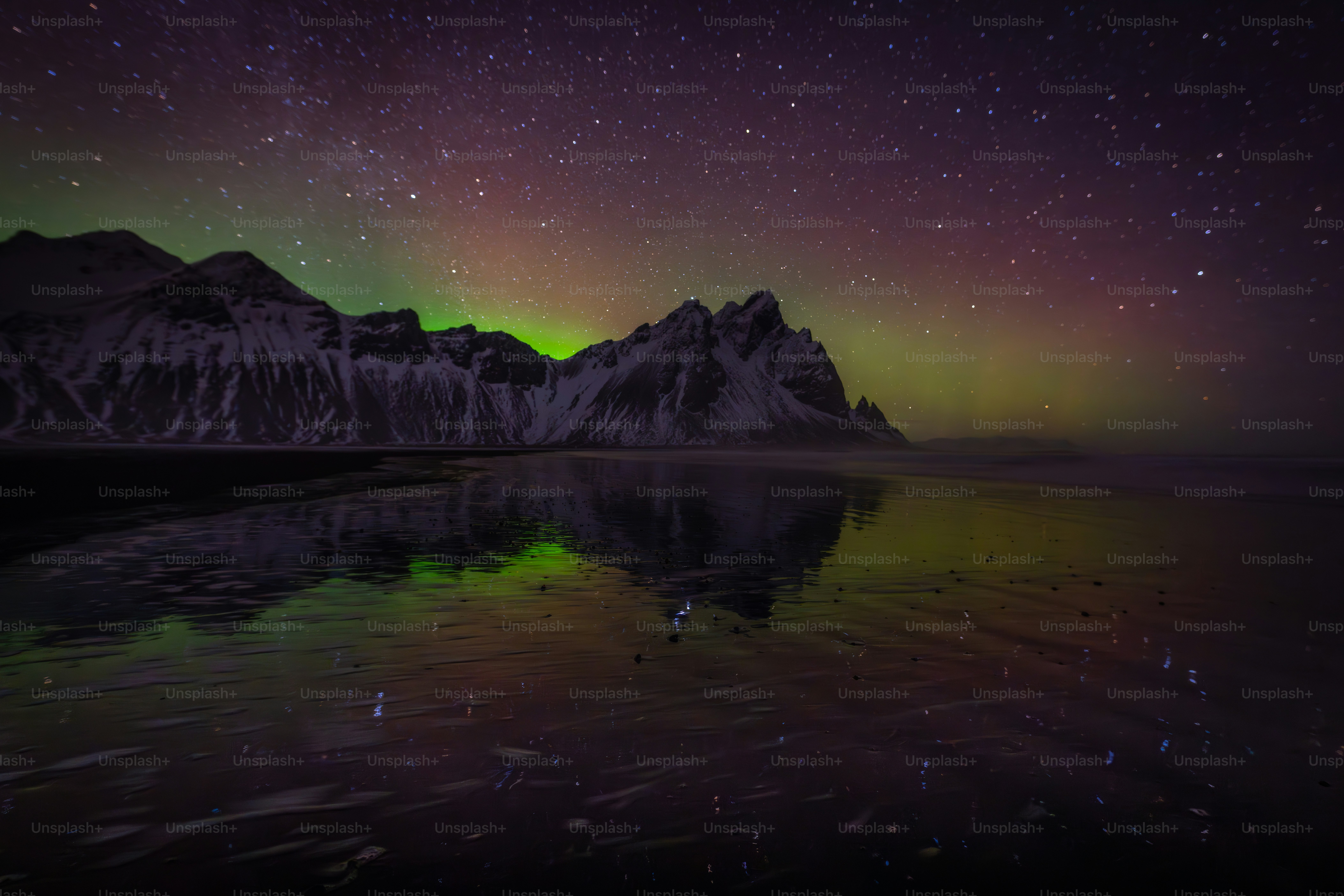 Aurora borealis over mountains reflected in water