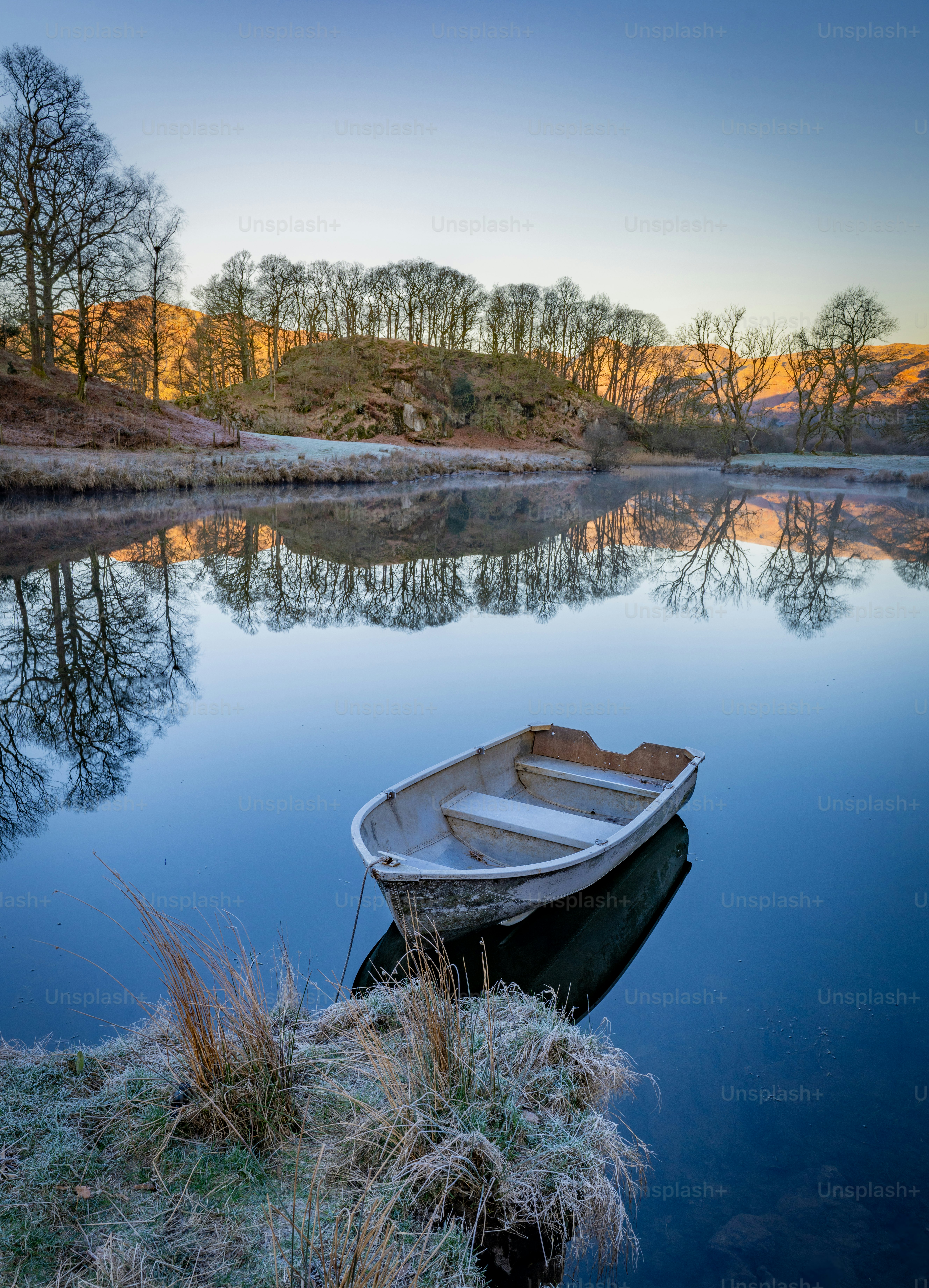 Ein einsames Ruderboot treibt auf einem ruhigen, reflektierenden See.