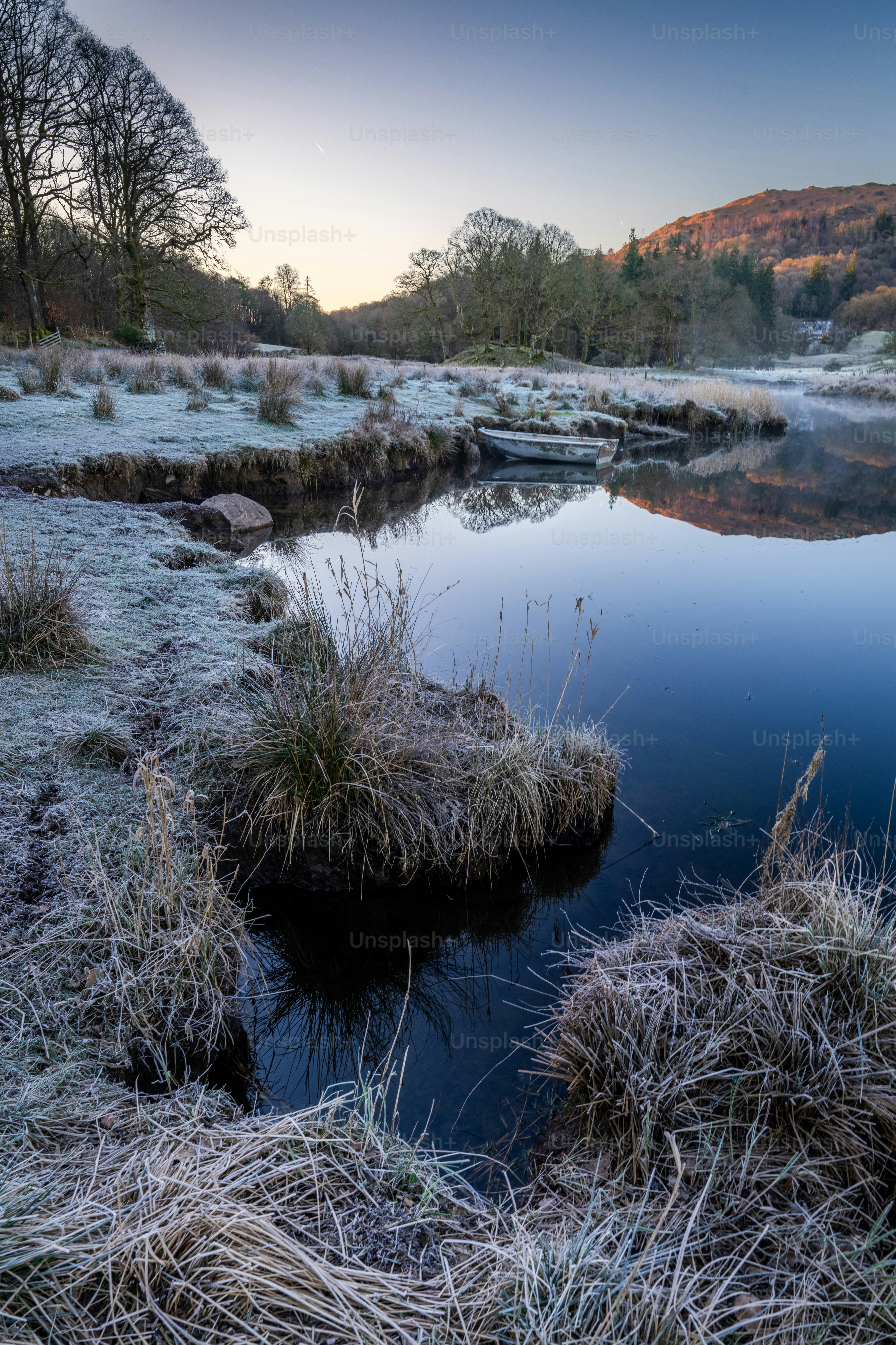 Frosty riverbank with calm water at sunrise