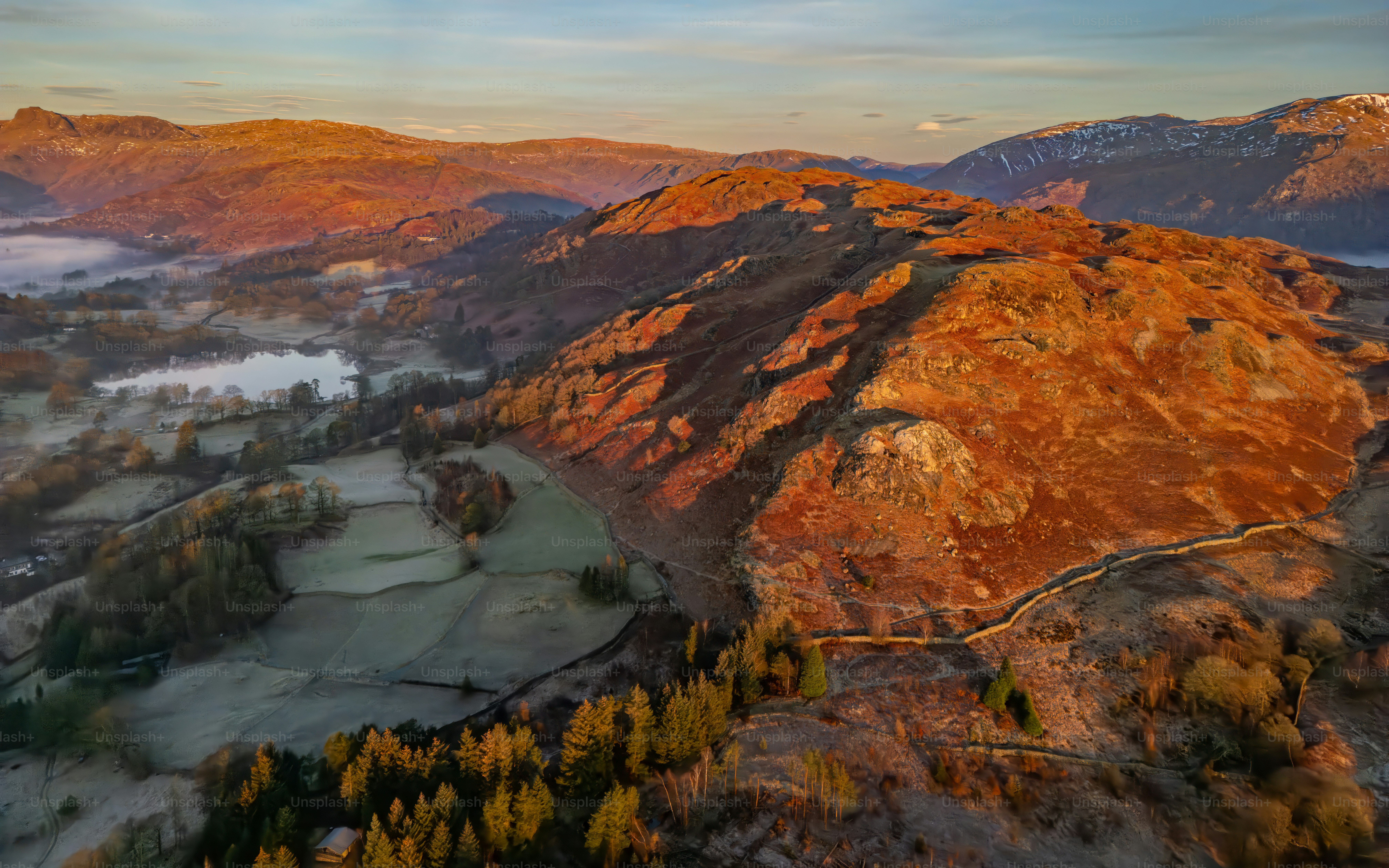 Golden sunrise illuminates a rugged mountain landscape with mist