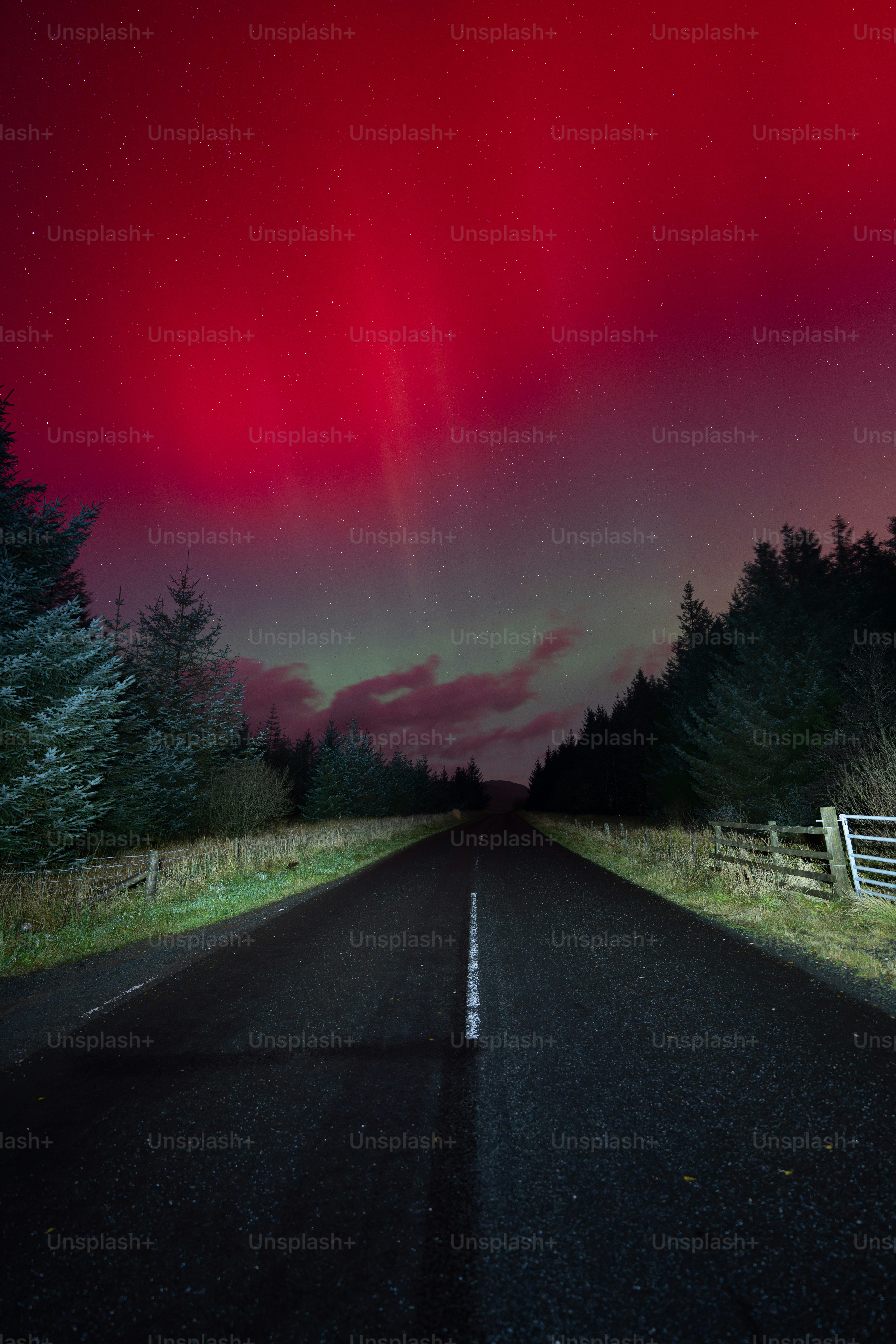 Straße unter dem leuchtend roten Polarlichthimmel