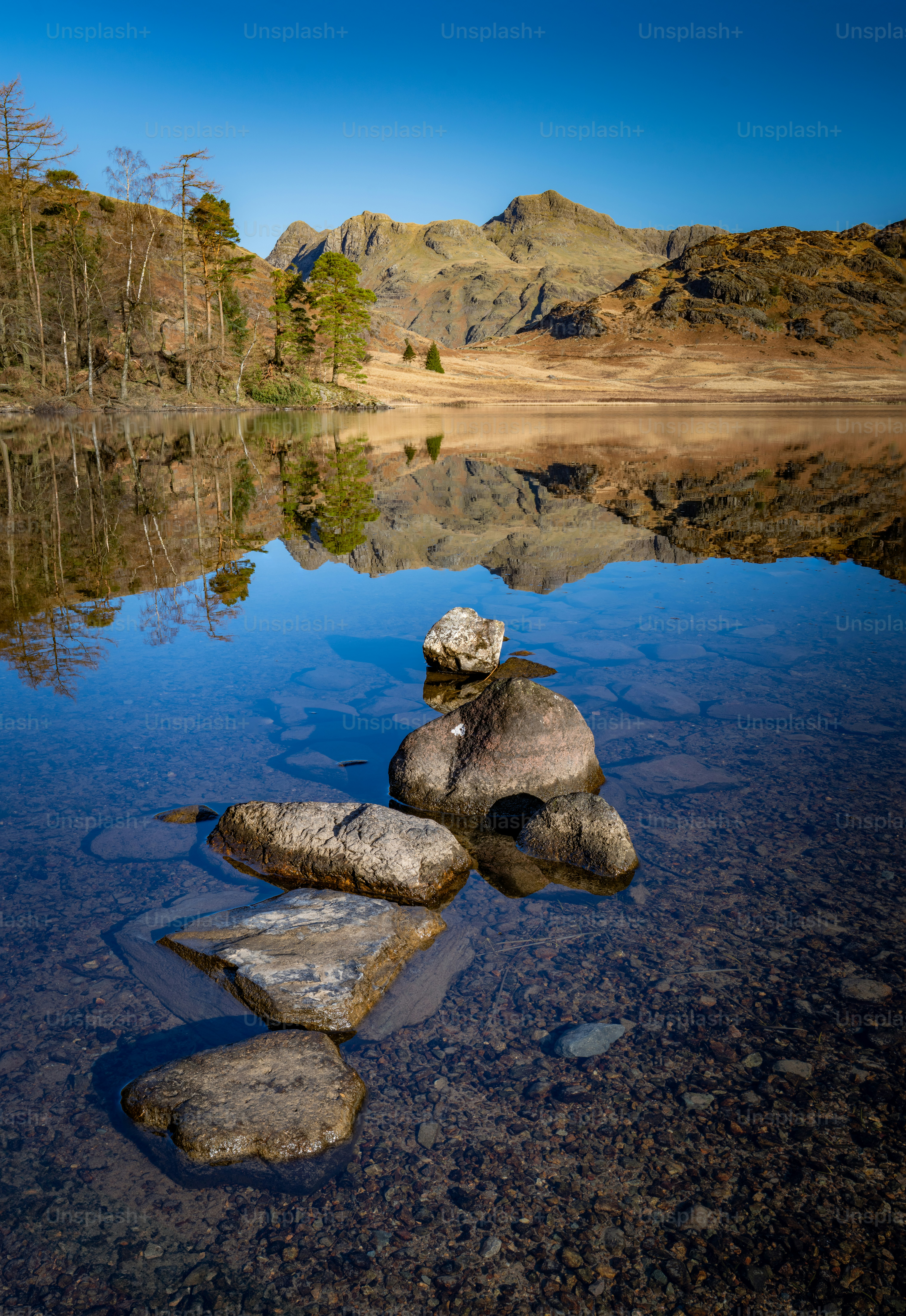 Calm lake reflecting mountains under a clear blue sky
