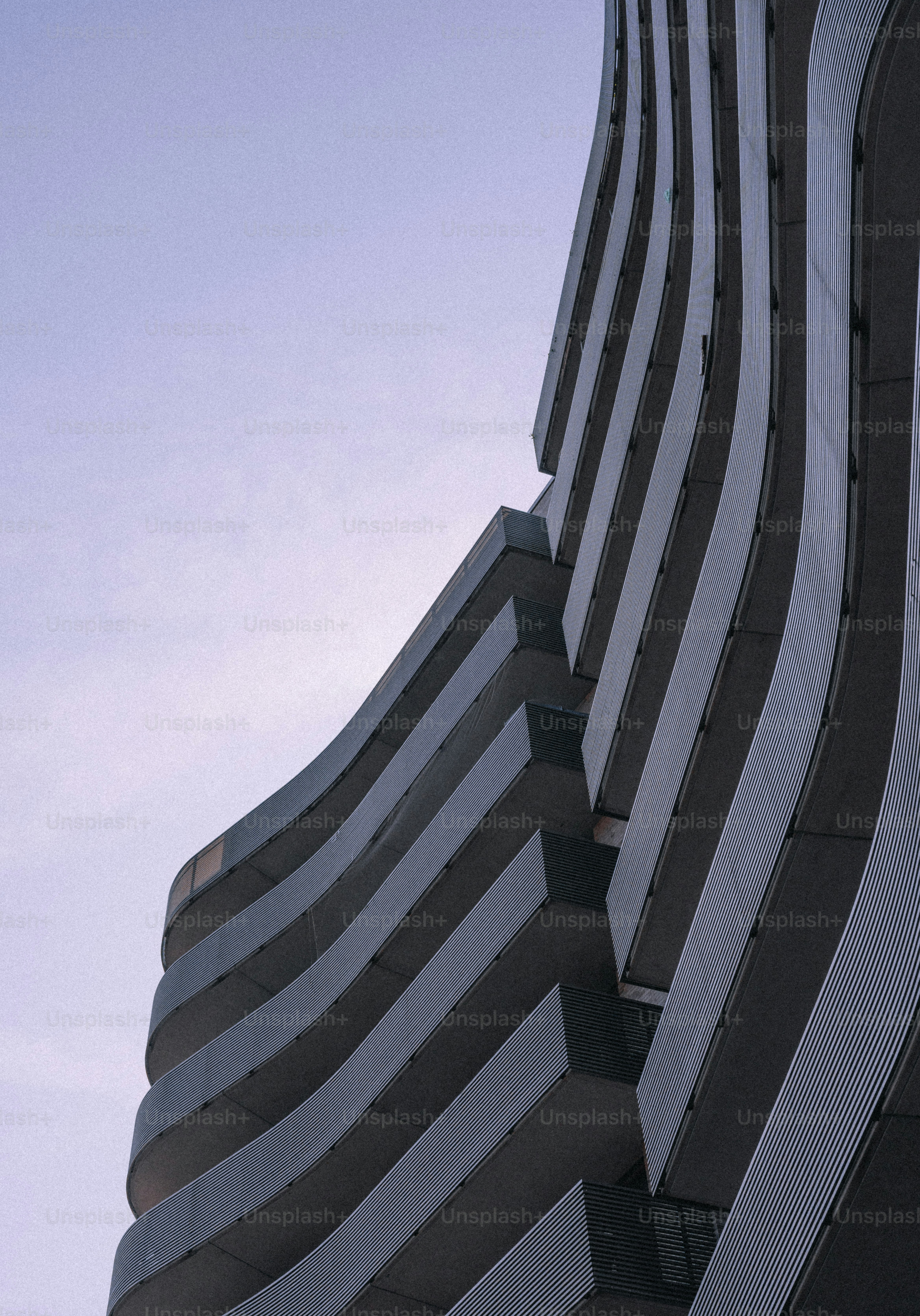 Edificio moderno con balcones curvados contra un cielo pálido