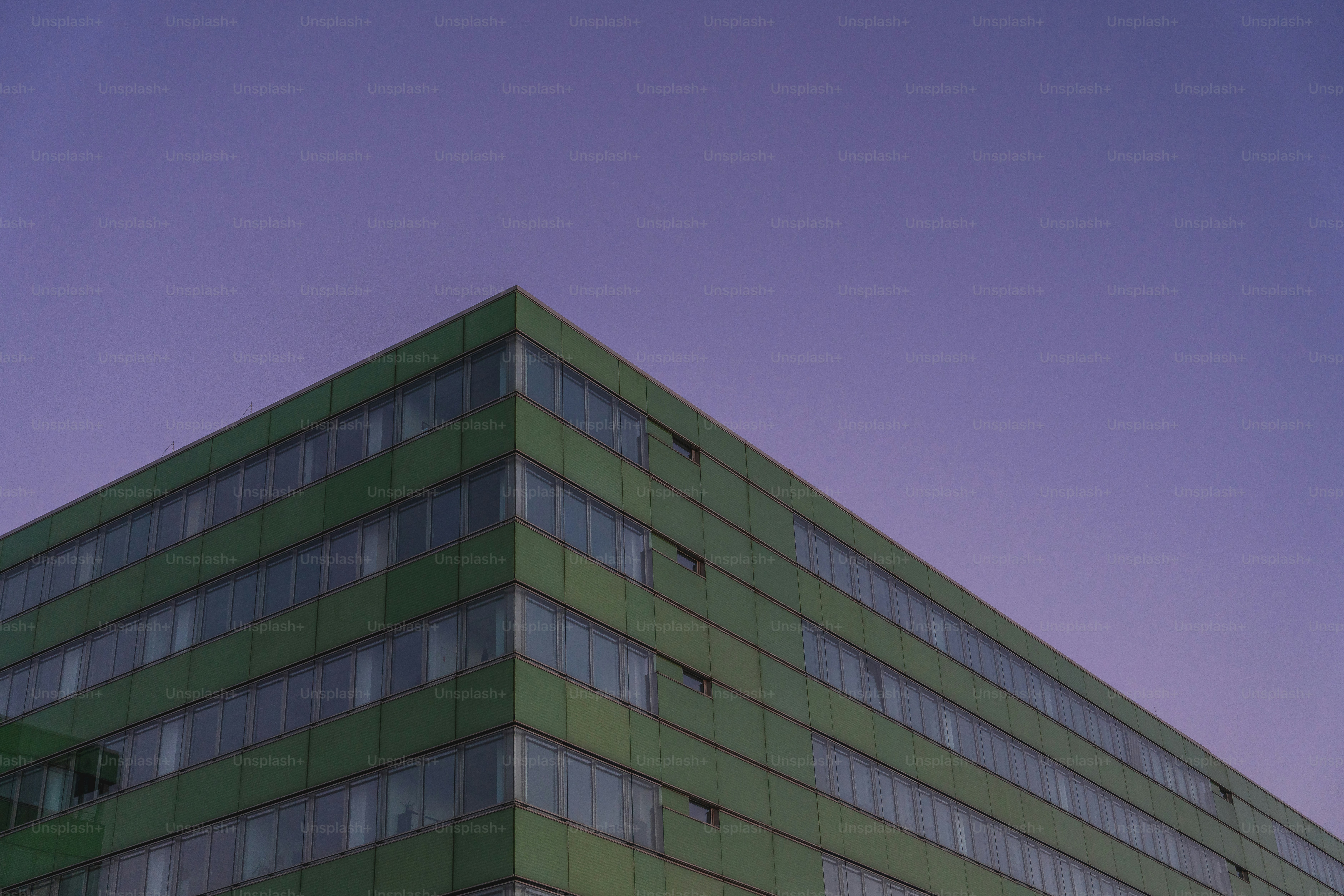 Esquina verde de edificio contra un cielo morado